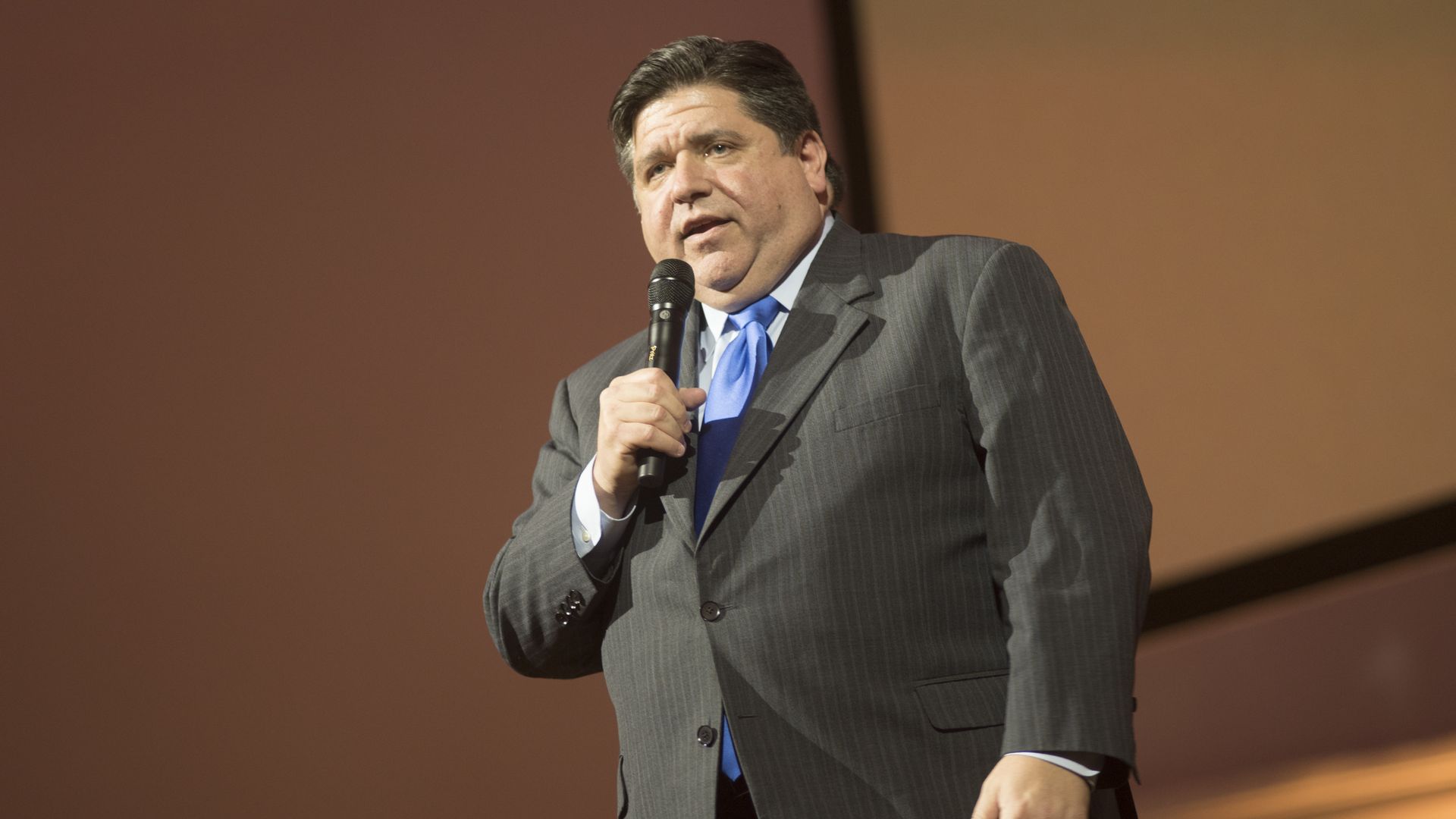 Photo of a man in a suit talking into a microphone 