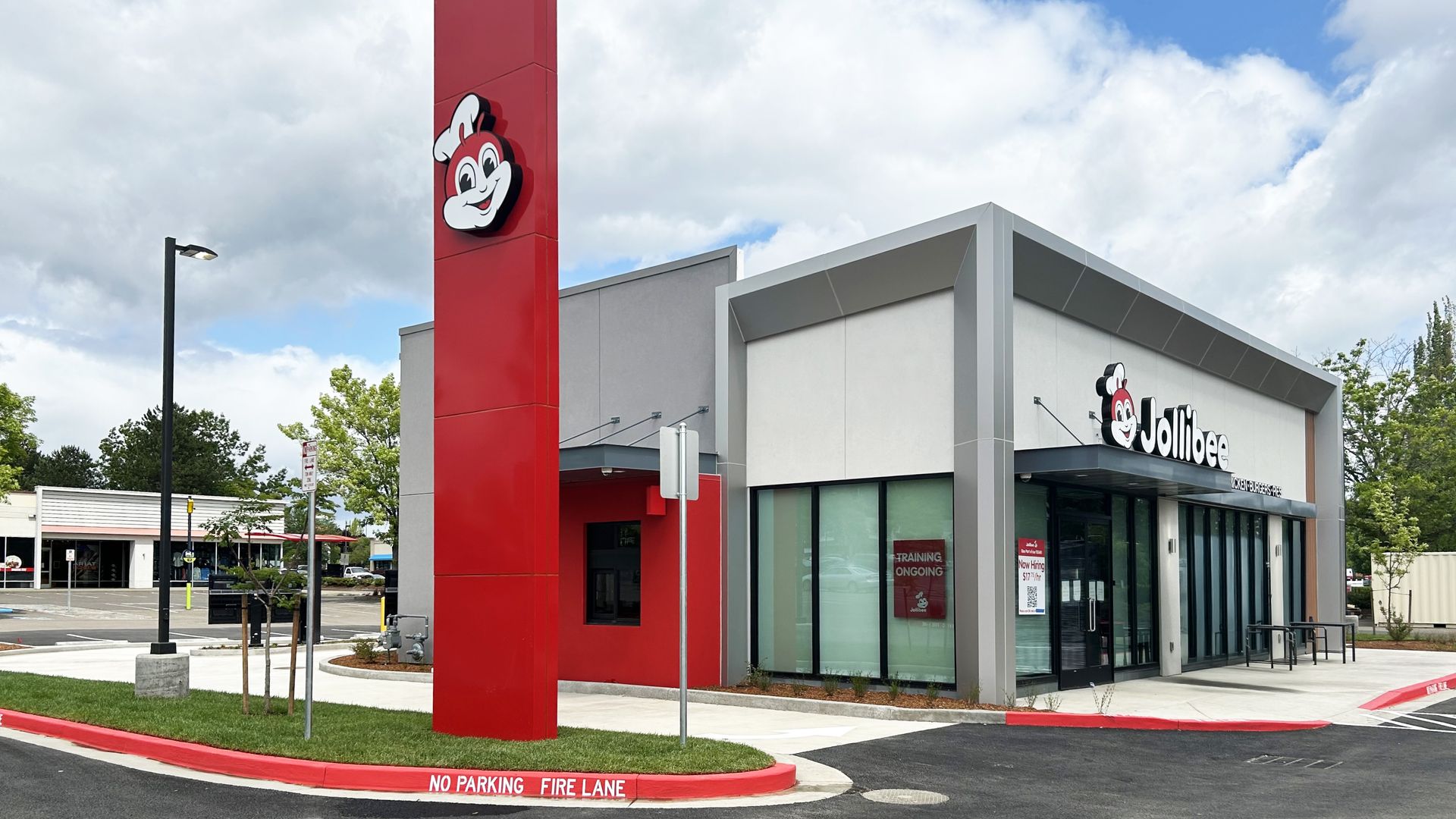 A photo of a storefront of a fast-food style drive-thru restaurant with red and white design, with a sign that says "Jollibee"