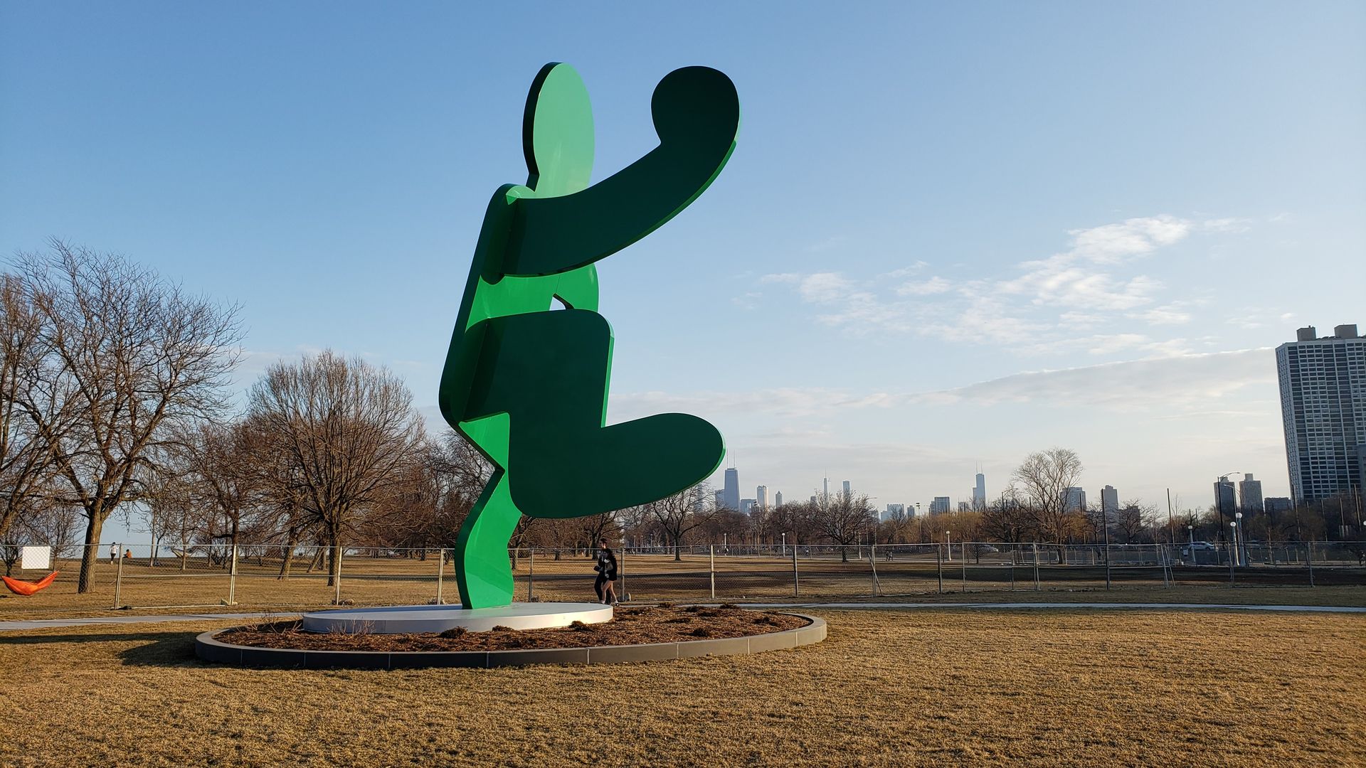 Photo of a green body scultpure in a park with the Chicago skyline behind it. 