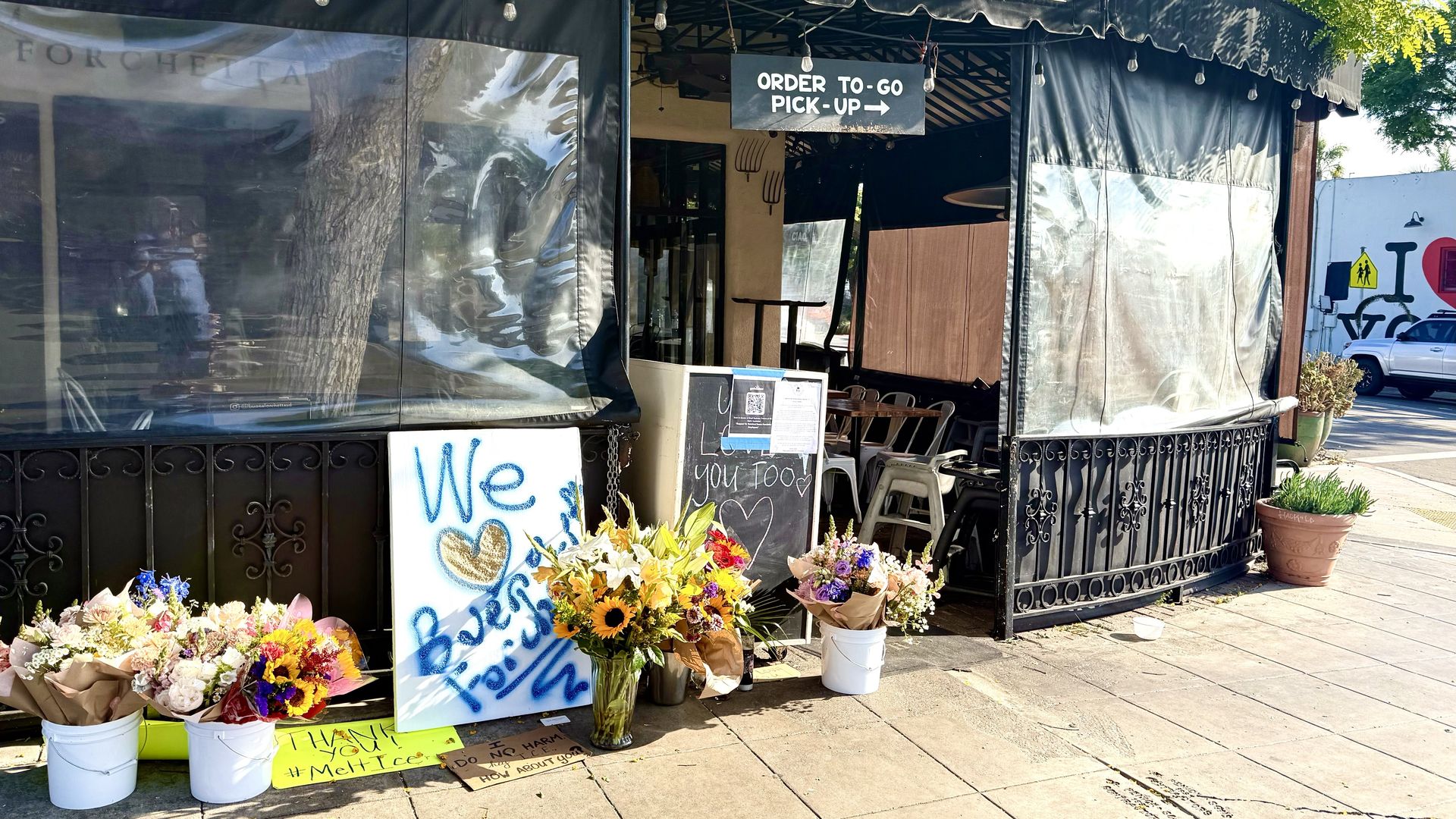 A community memorial of flowers and signs outside Buona Forchetta