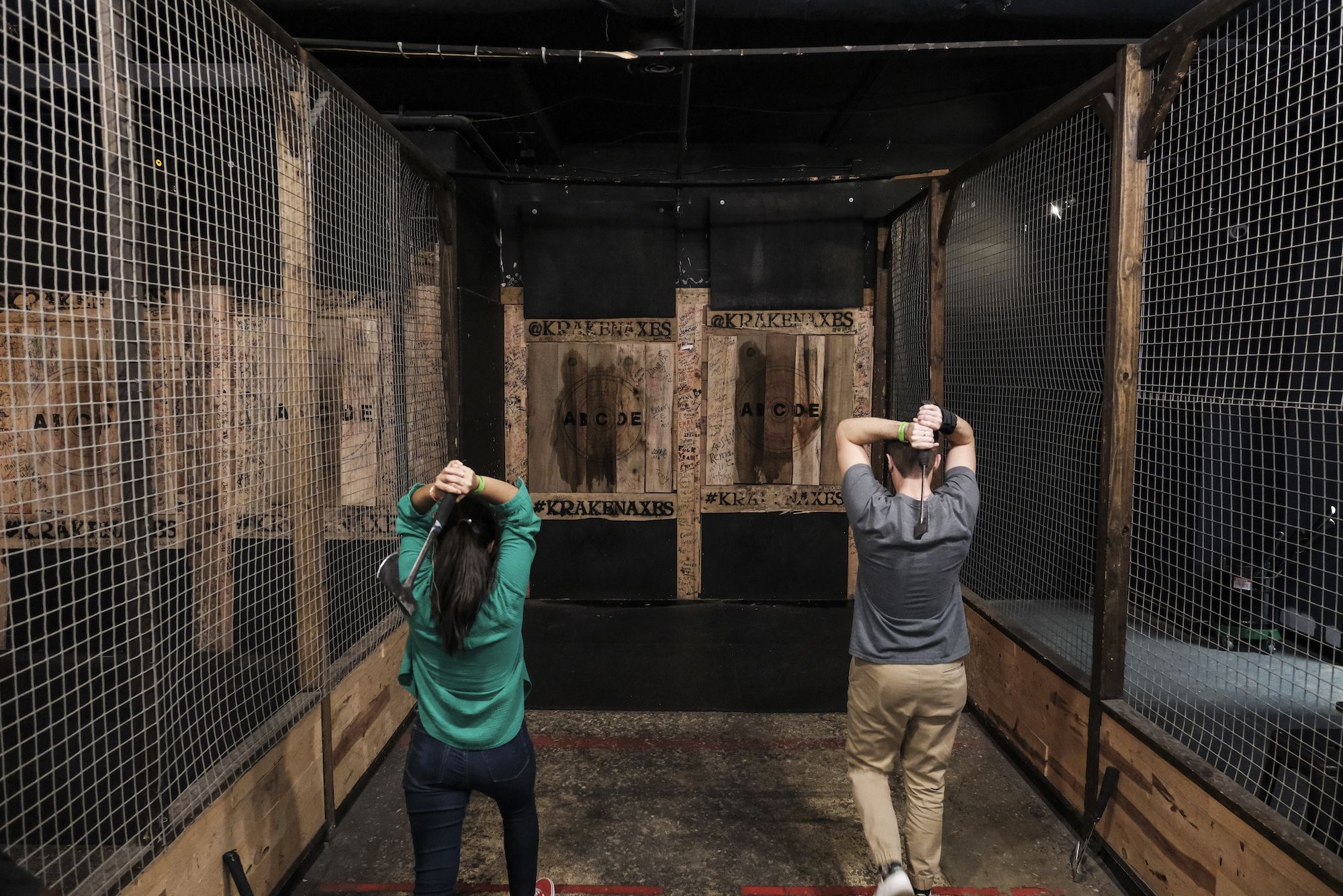 Two people prepare to throw axes in an axe throwing range in DC