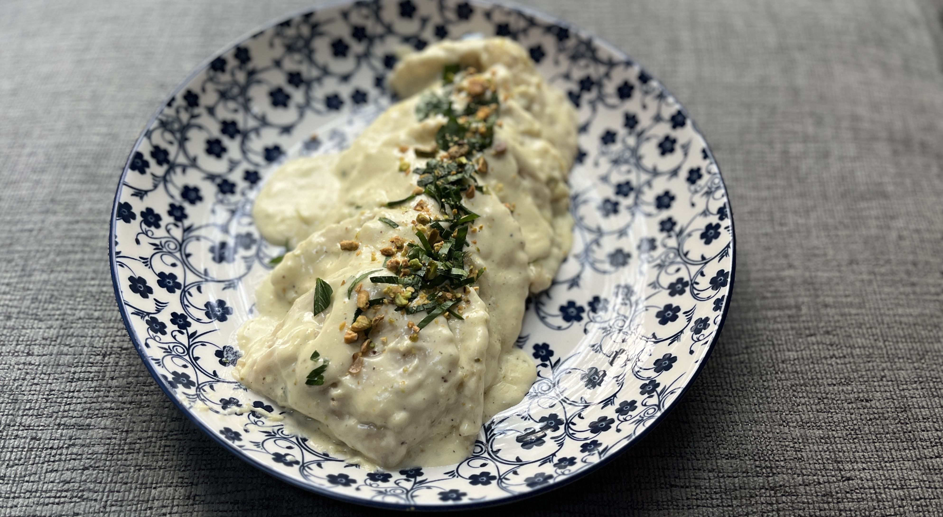 plate of ravioli covered in a cream sauce 