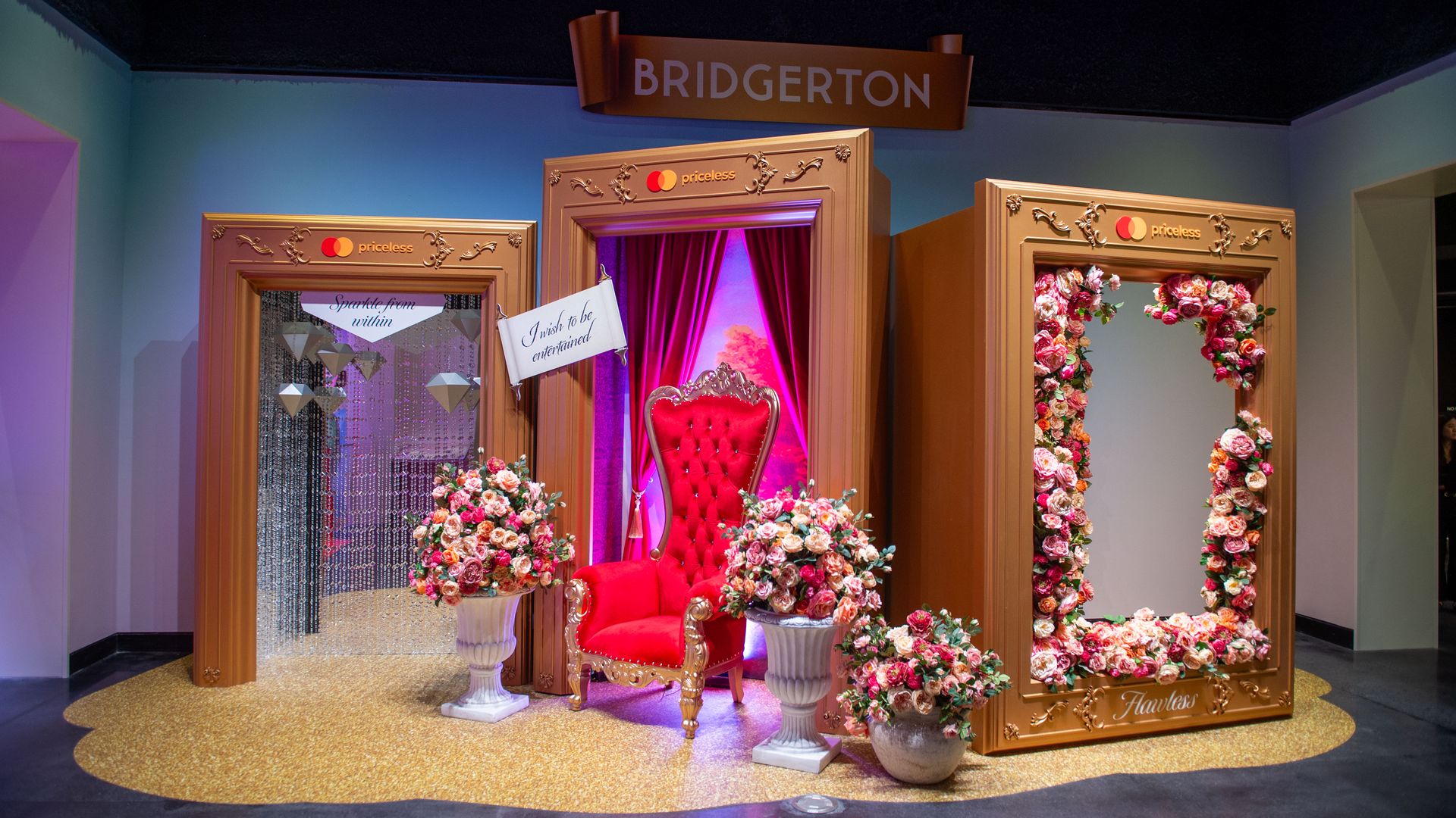 A display with a red chair and gold boxes that people can stand inside for photos
