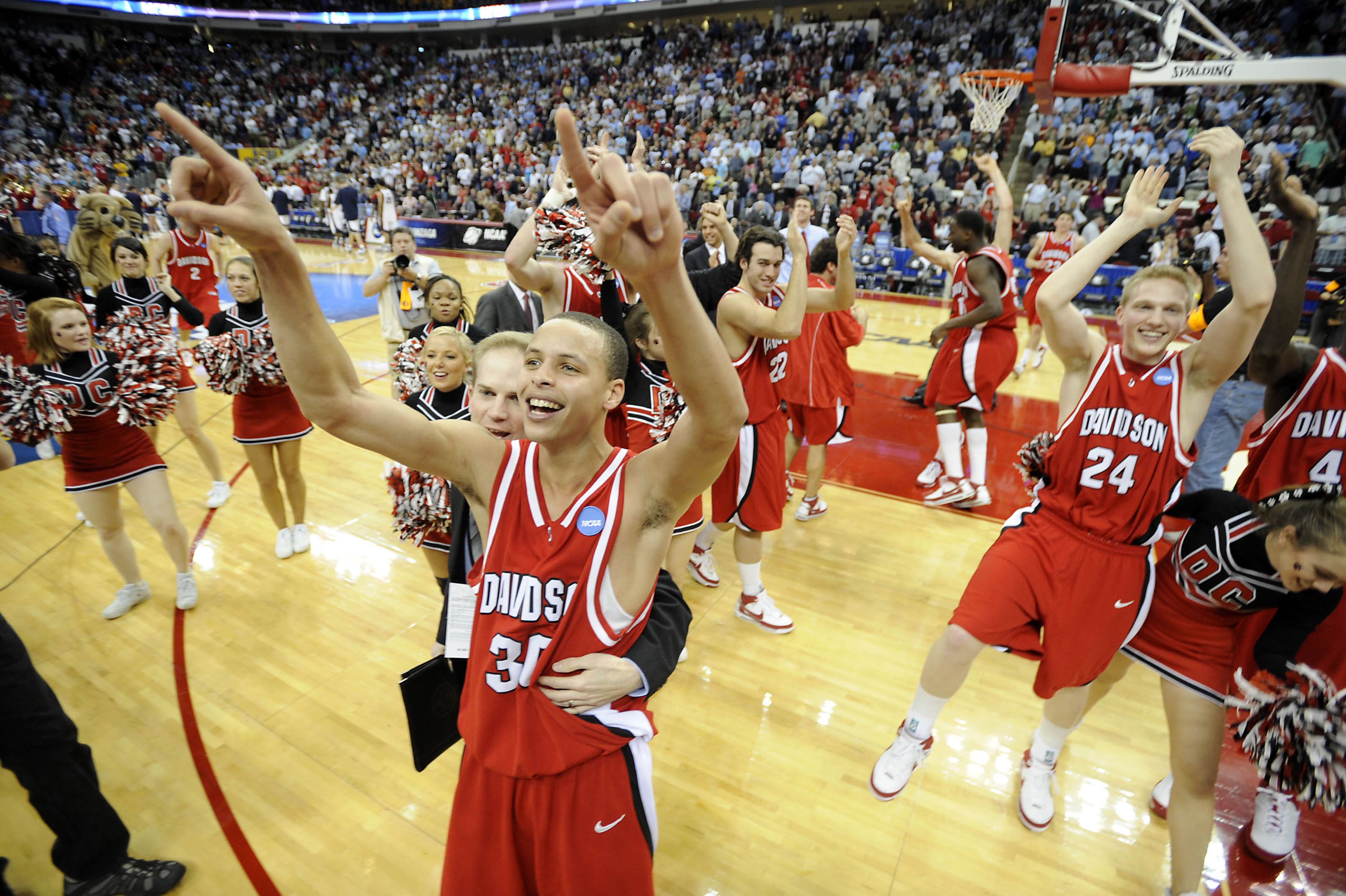 Steph Curry celebrates with other Davidson players on the basketball court. 