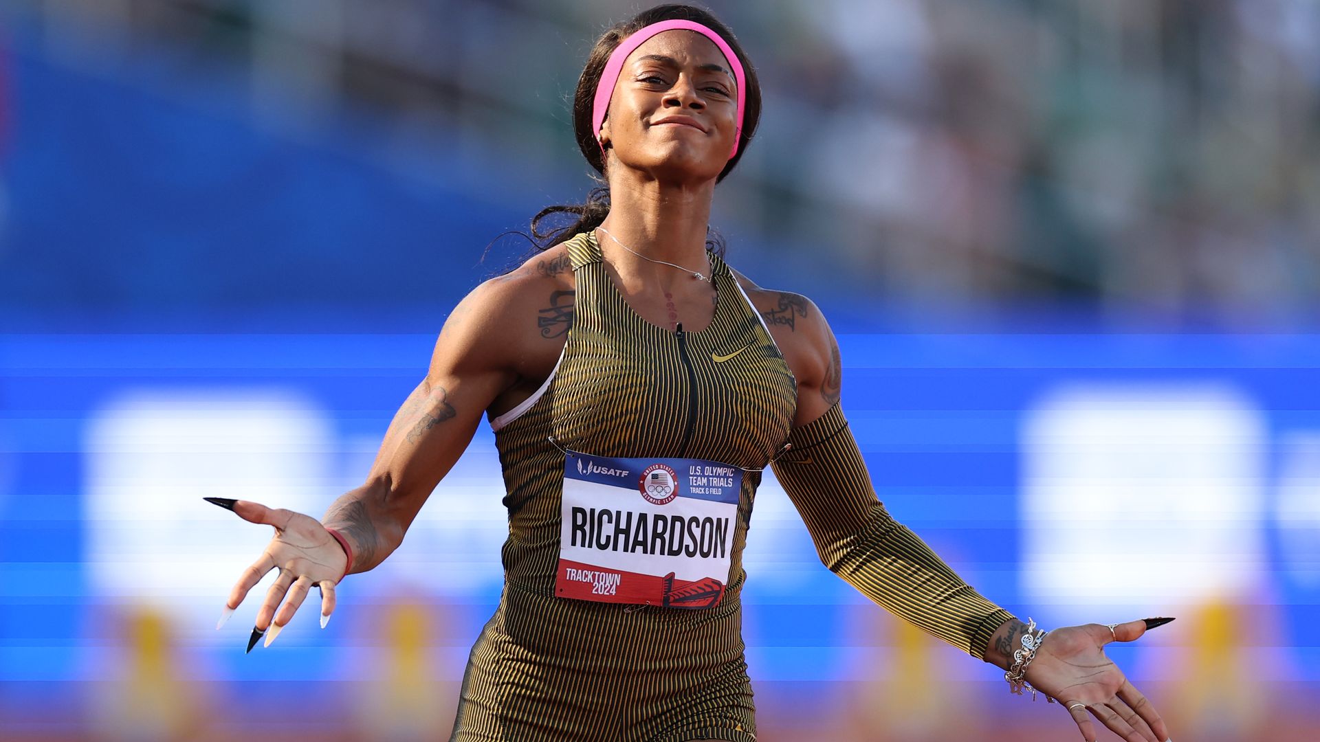 Sha'Carri Richardson throws her arms wide as she finishes a race.