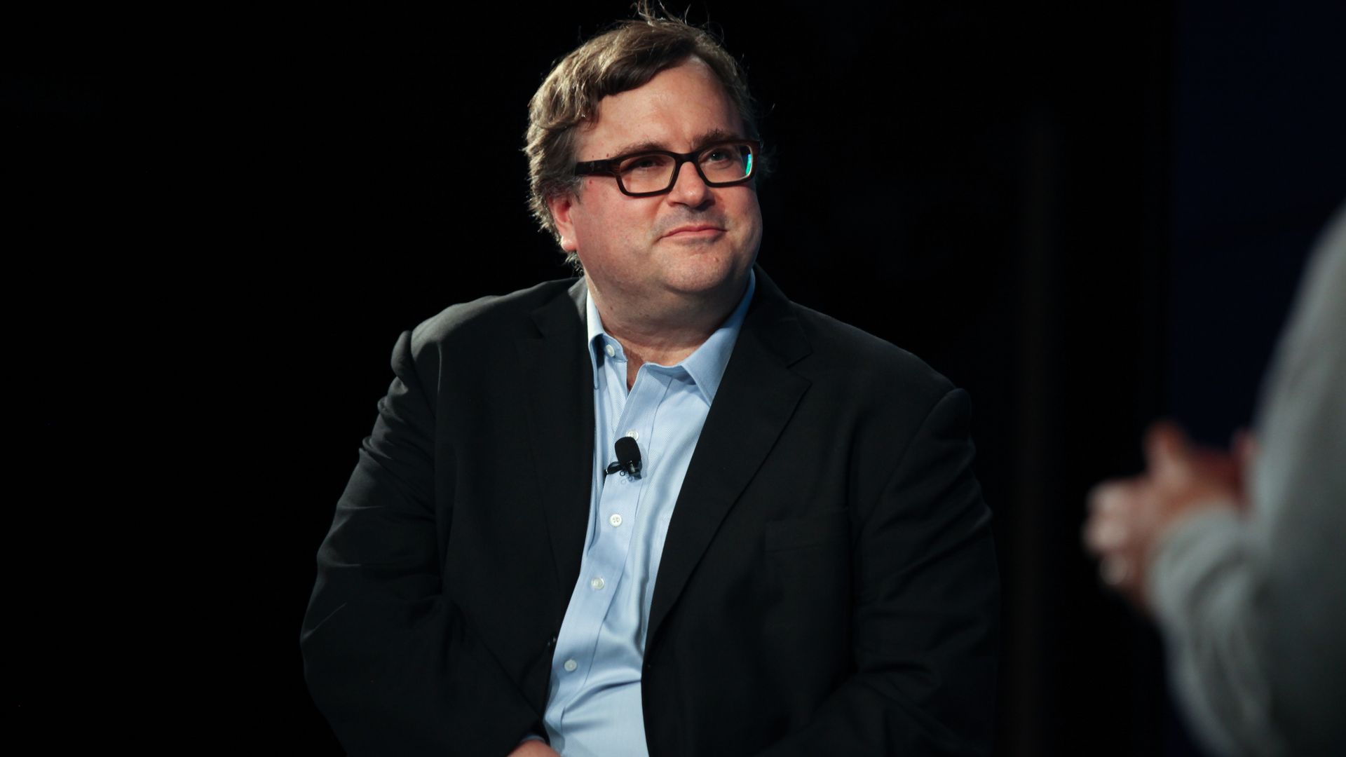 Reid Hoffman sitting on a stage for an event. 