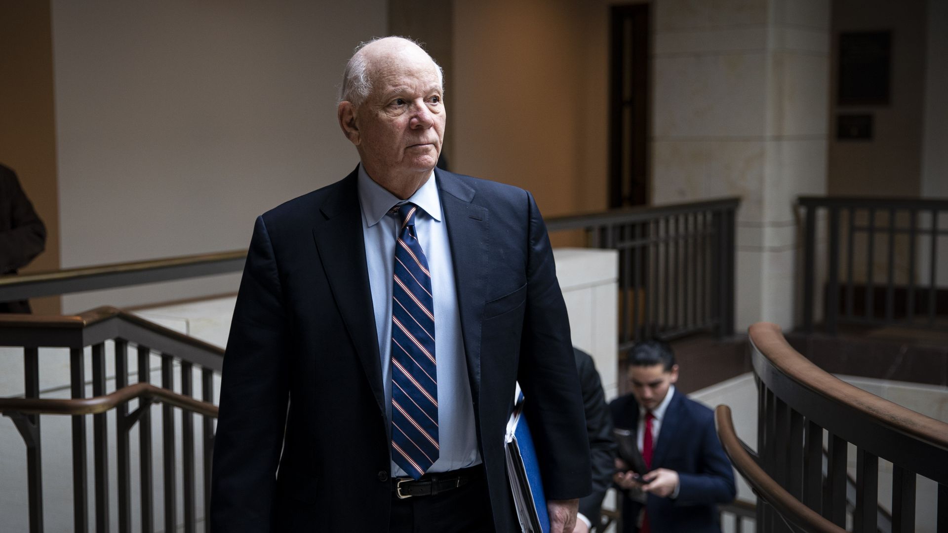 Sen. Ben Cardin, wearing a blue suit, light blue shirt and blue-and-yellow striped tie, walks up the stairs from the Senate SCIF.