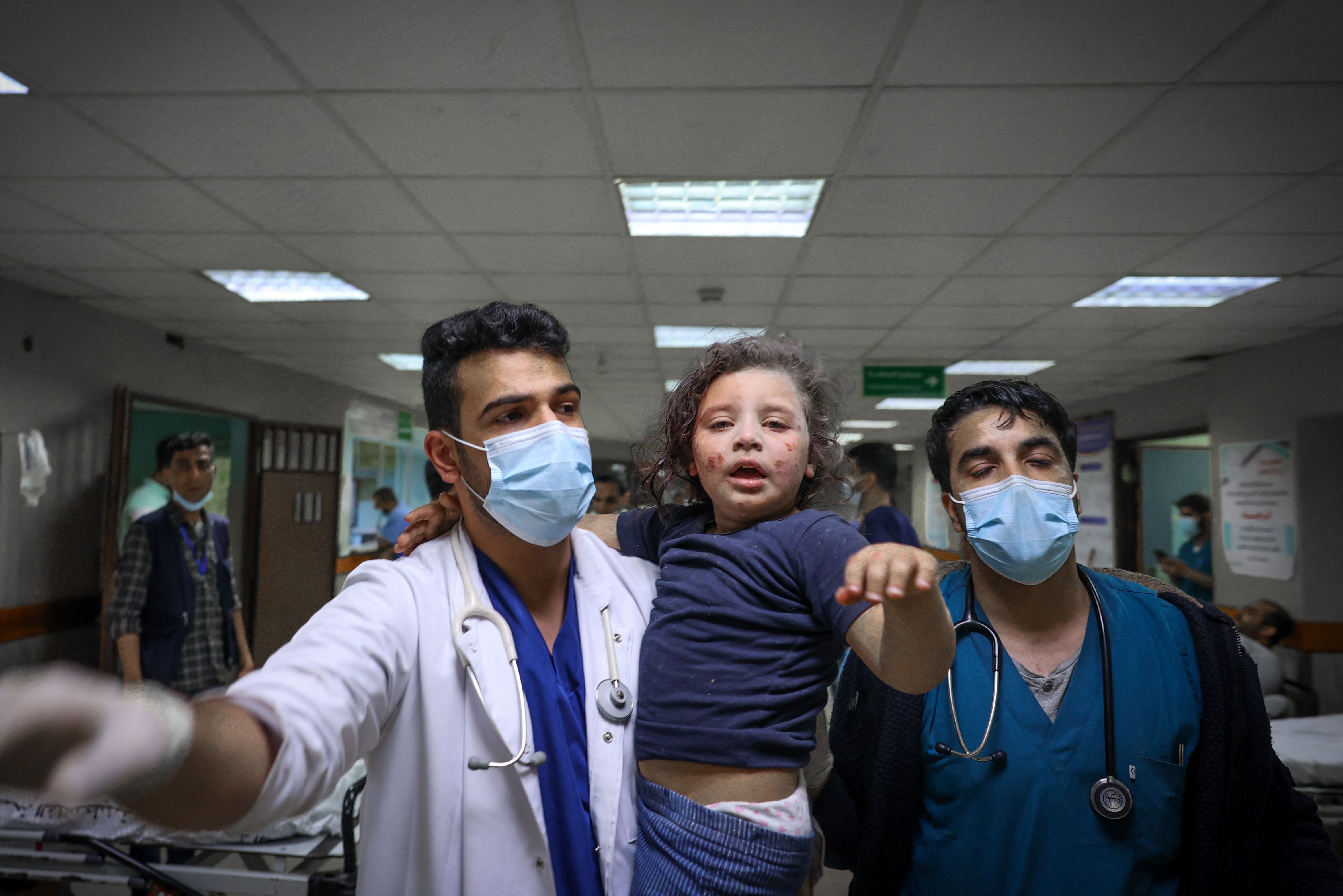  Palestinian doctors rush to treat a wounded girl who arrived with her family at Al-Shifa Hospital after intensive bombardments in Gaza City, 16 