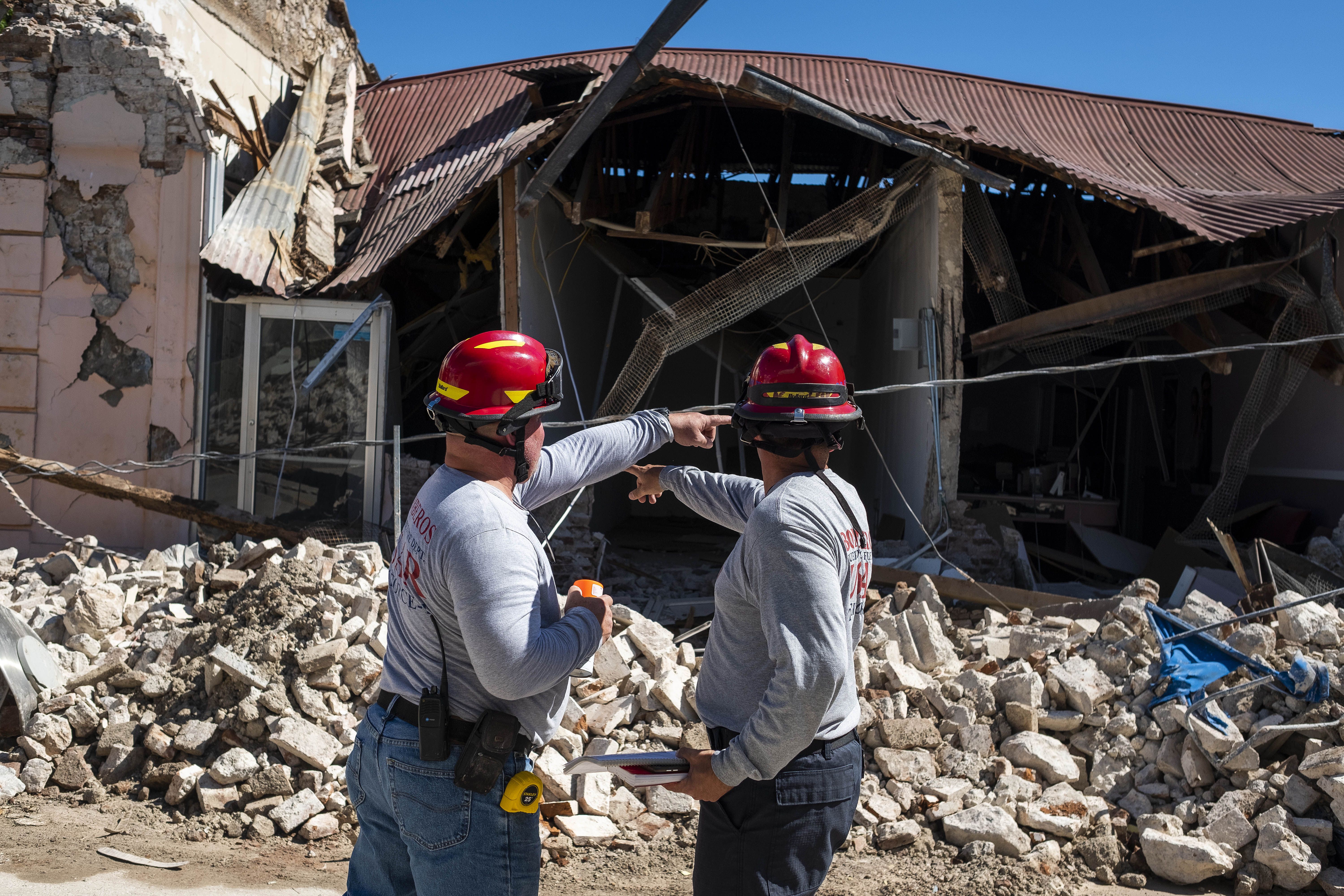  Two firemen survey a collapsed building after an earthquake hit the island in Guanica, Puerto Rico