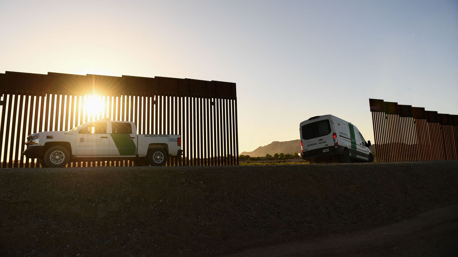 Photo of vans parked beside a gap in the border wall