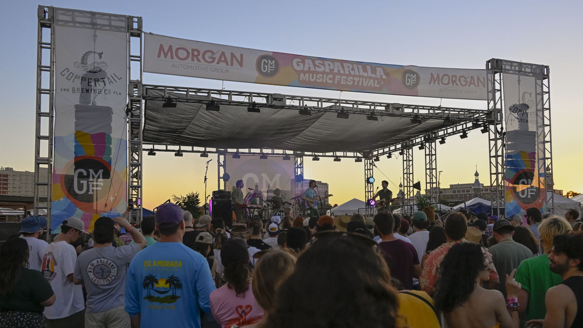 Fans watch musicians perform on a Gasparilla Music Festival stage at sunset.
