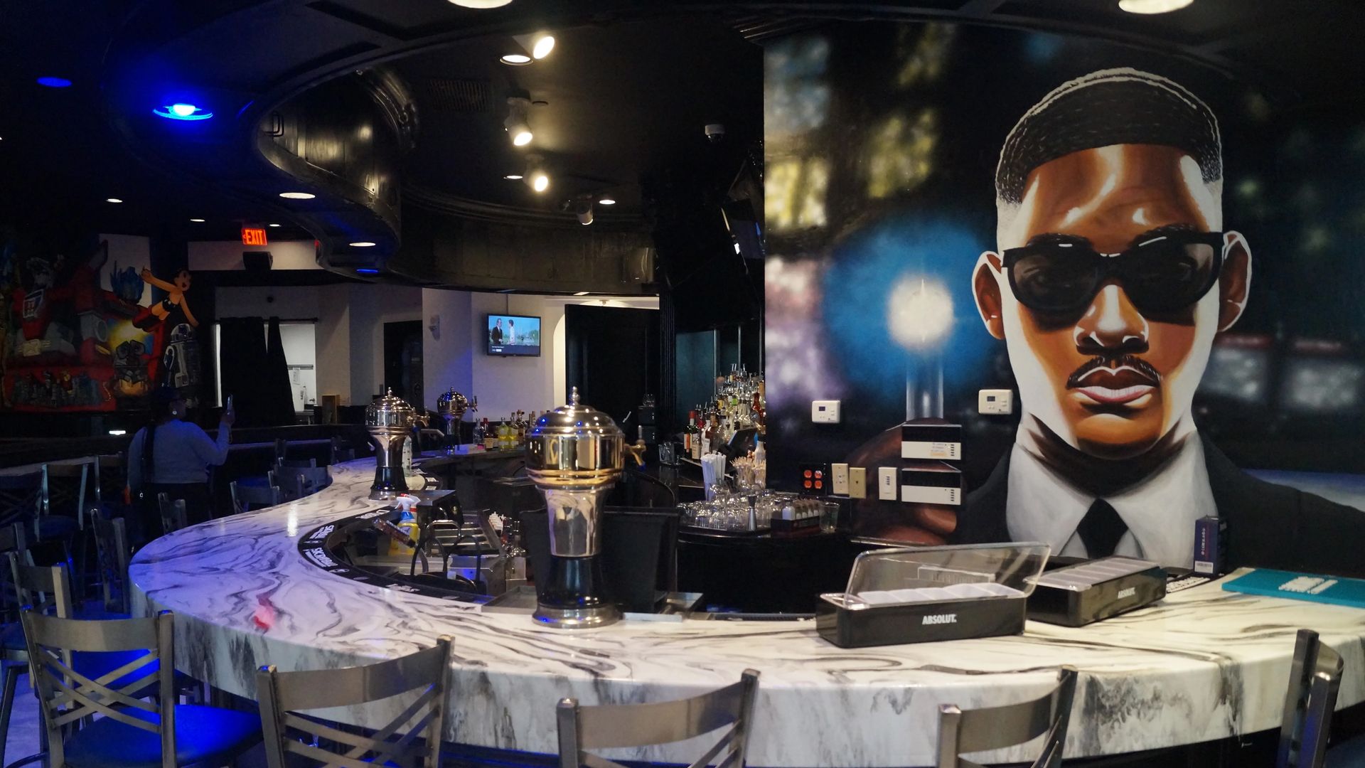 bar seating with artwork of will smith in "men in black" behind the bar