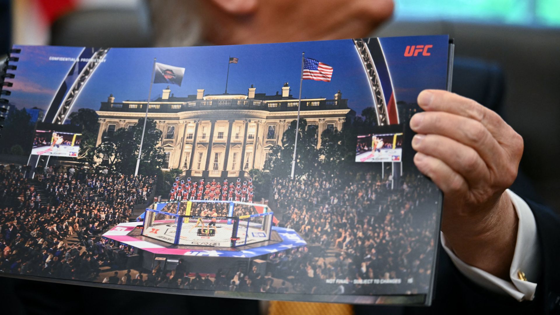Close-up of a suited Trump holding a large UFC booklet showing a grand building with flags, a large crowd, and a boxing ring in the foreground; UFC logo visible.