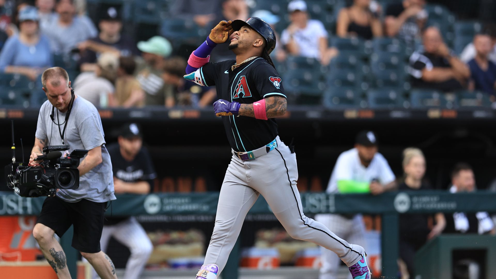 Photo of a baseball player trotting on a baseball diamond pointing to the sky.