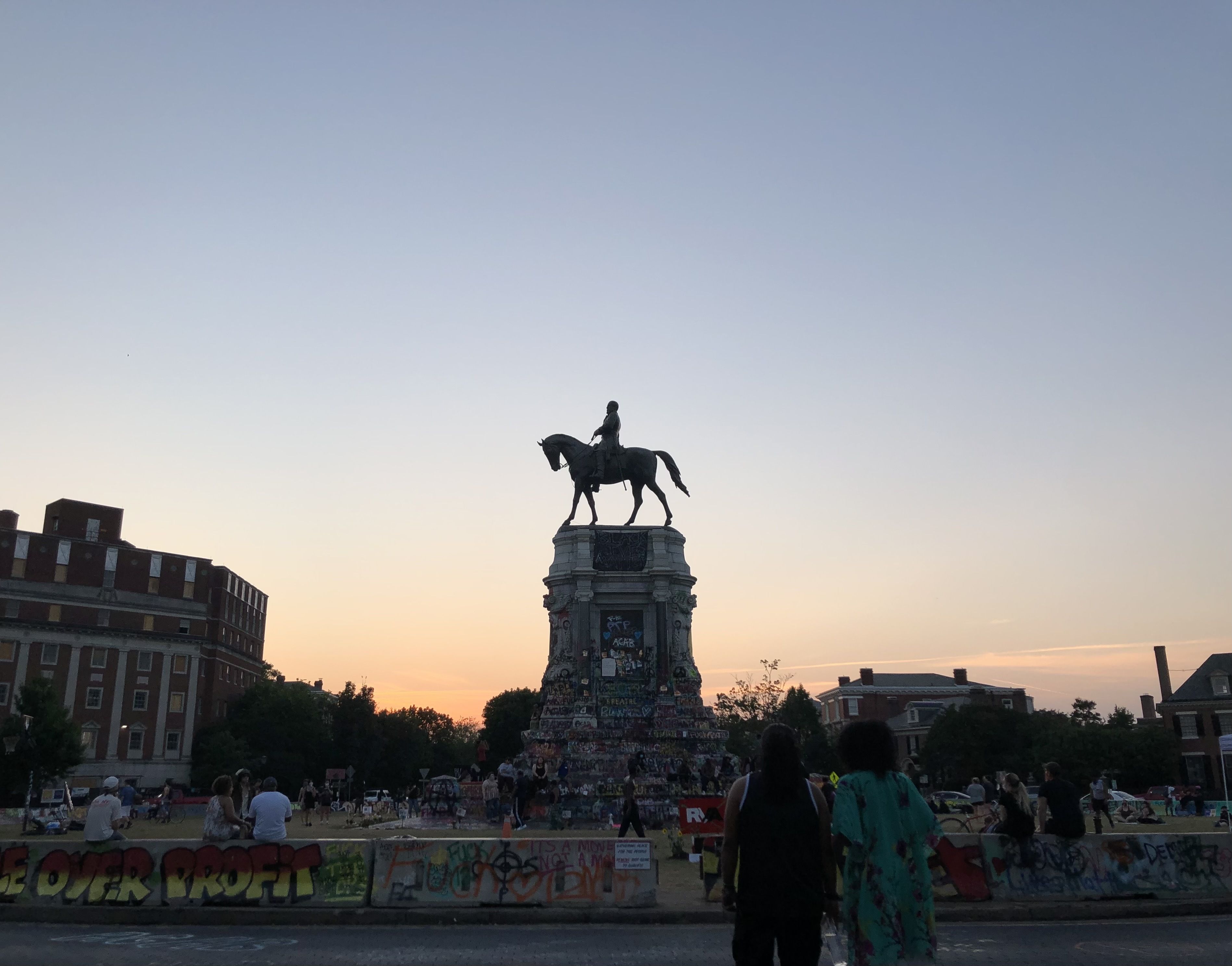 A picture of a crowd at the Lee Monument at sunset before the statue and the graffitied pedestal were removed.