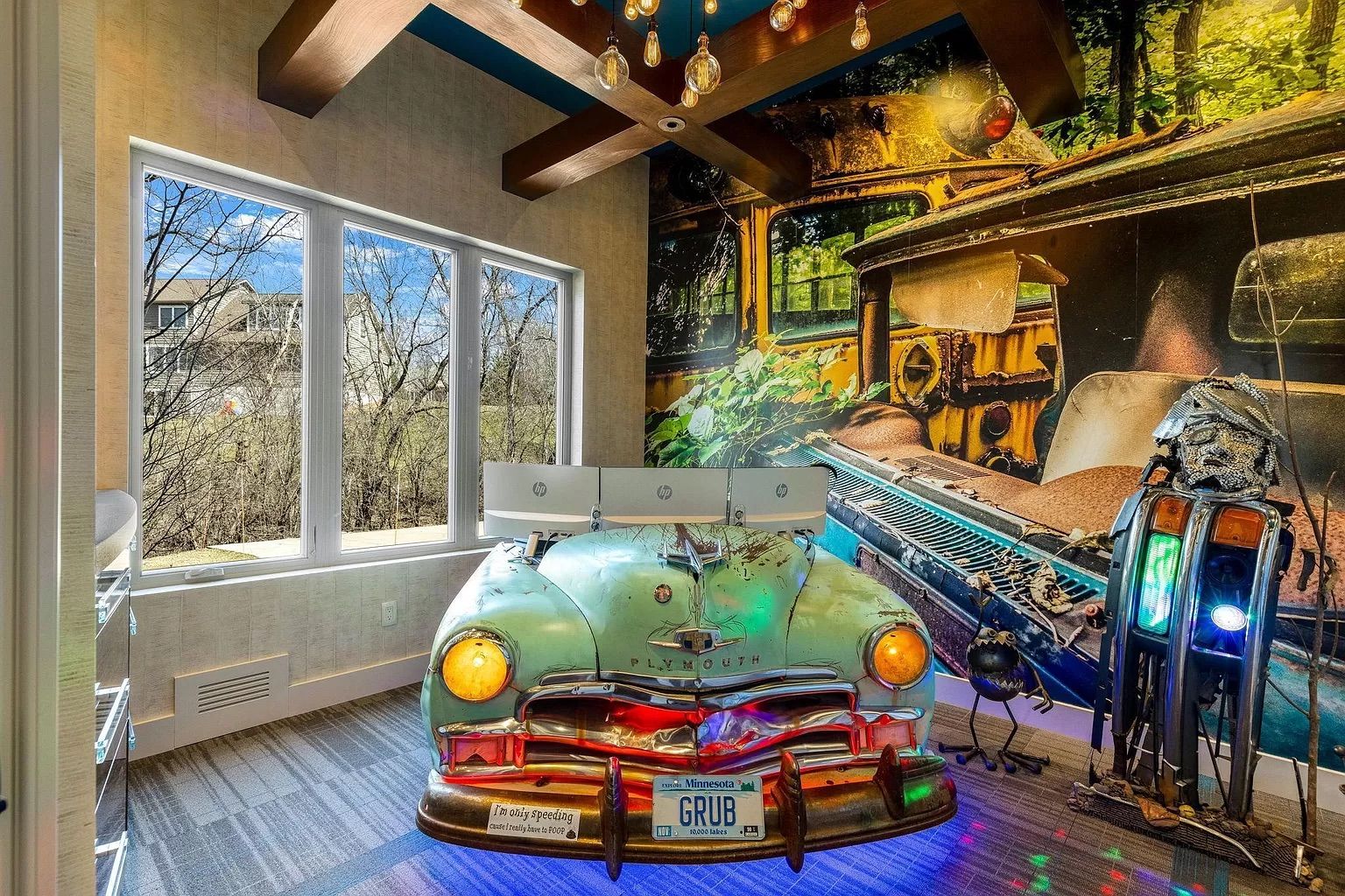 A room with a colorful steampunk mural and a car.