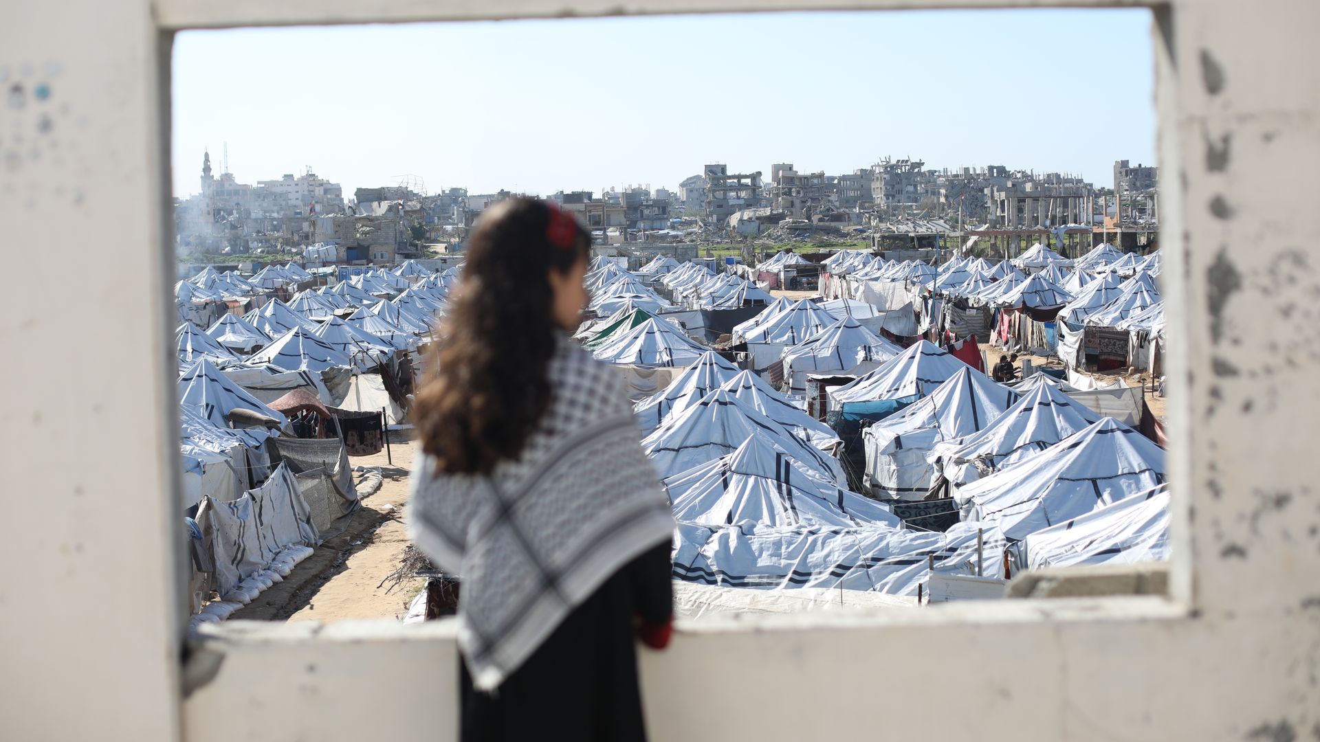 Girl looking at tents and rubble