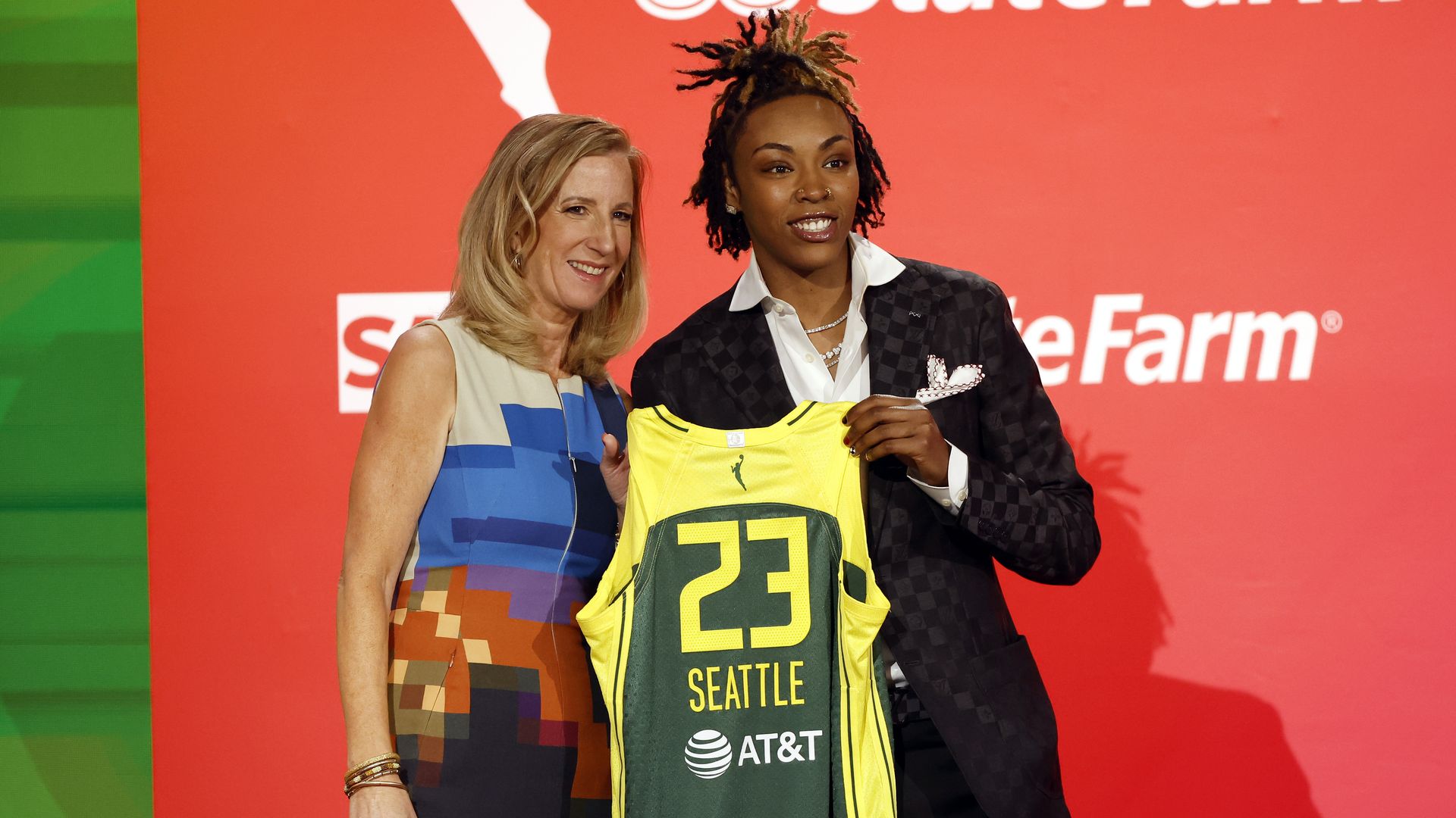 WNBA draftee Jordan Horston holds up a Seattle Storm uniform next to the WNBA commissioner. 