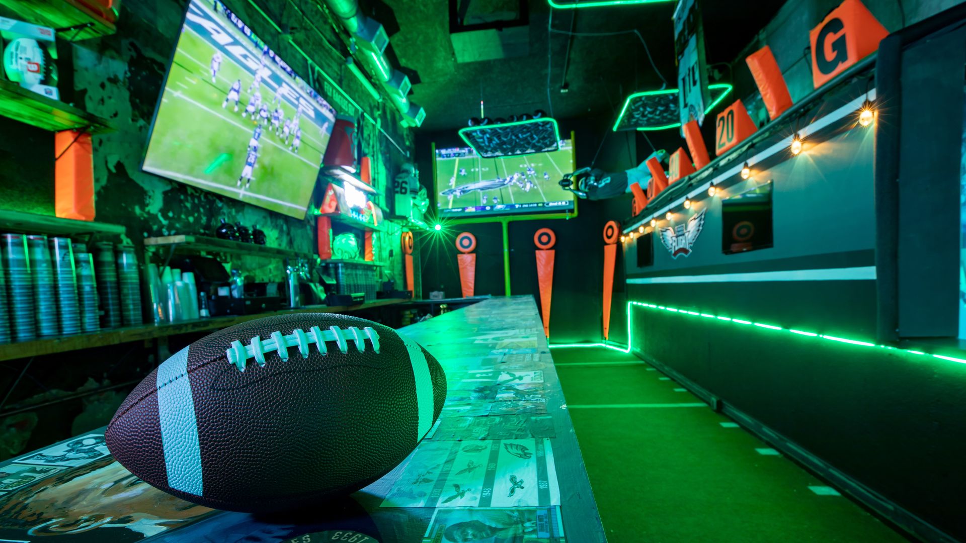 A football sitting on a bar in front of televisions