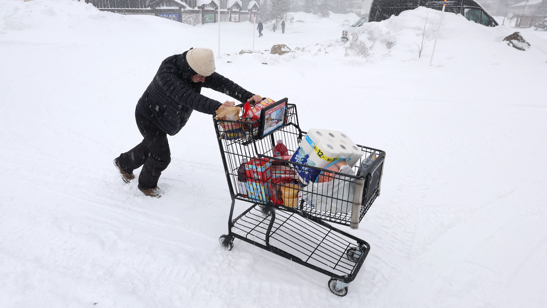 Person pushes a cart full of groceries during a winter storm