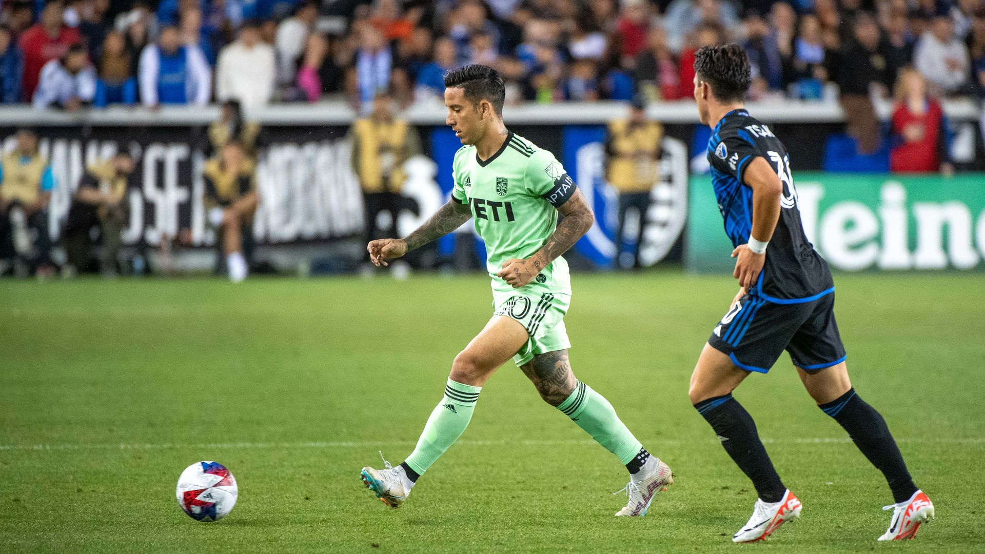 Two soccer players run down the turf.