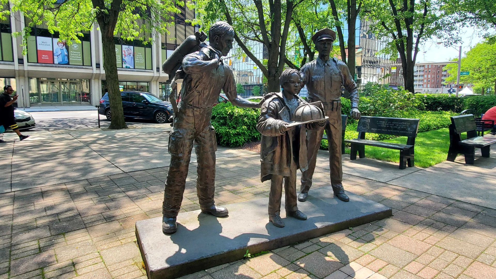 A statue of a police officer, firefighter and boy in a park. 