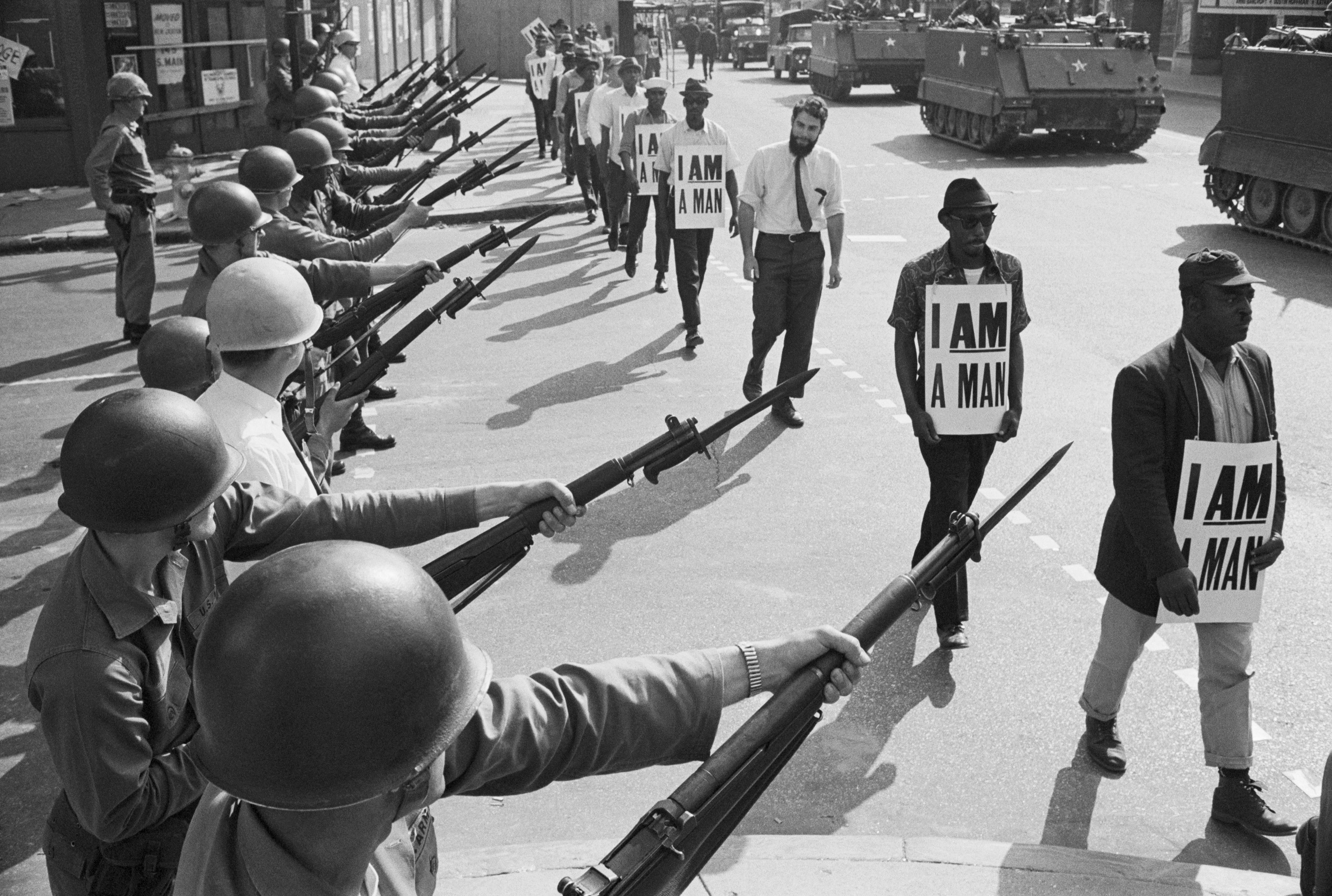 U.S. National Guard troops block off Beale Street in Memphis as Civil Rights marchers wearing placards reading, "I AM A MAN" pass by on March 29, 1968. 
