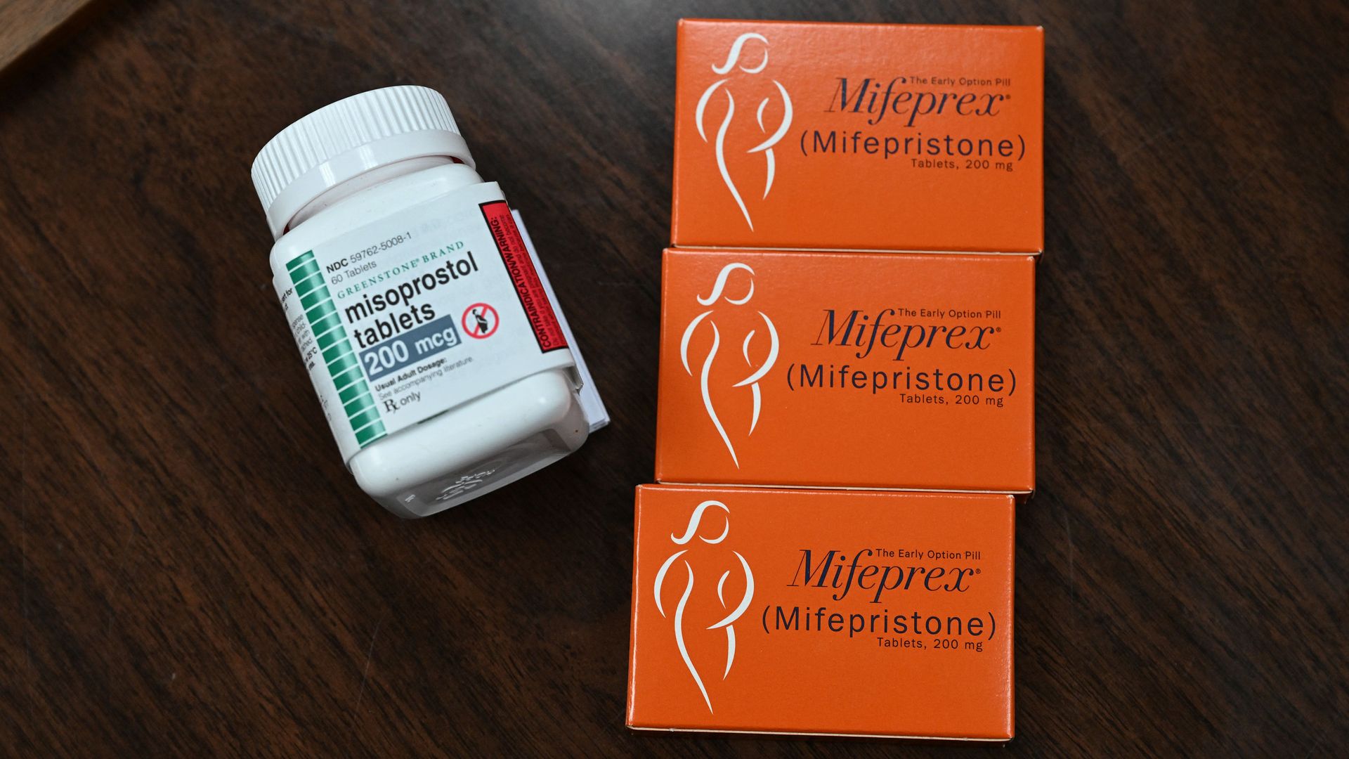 A pill bottle labeled as misoprostol sits next to three pill boxes labeled as Mifeprex (mifepristone).