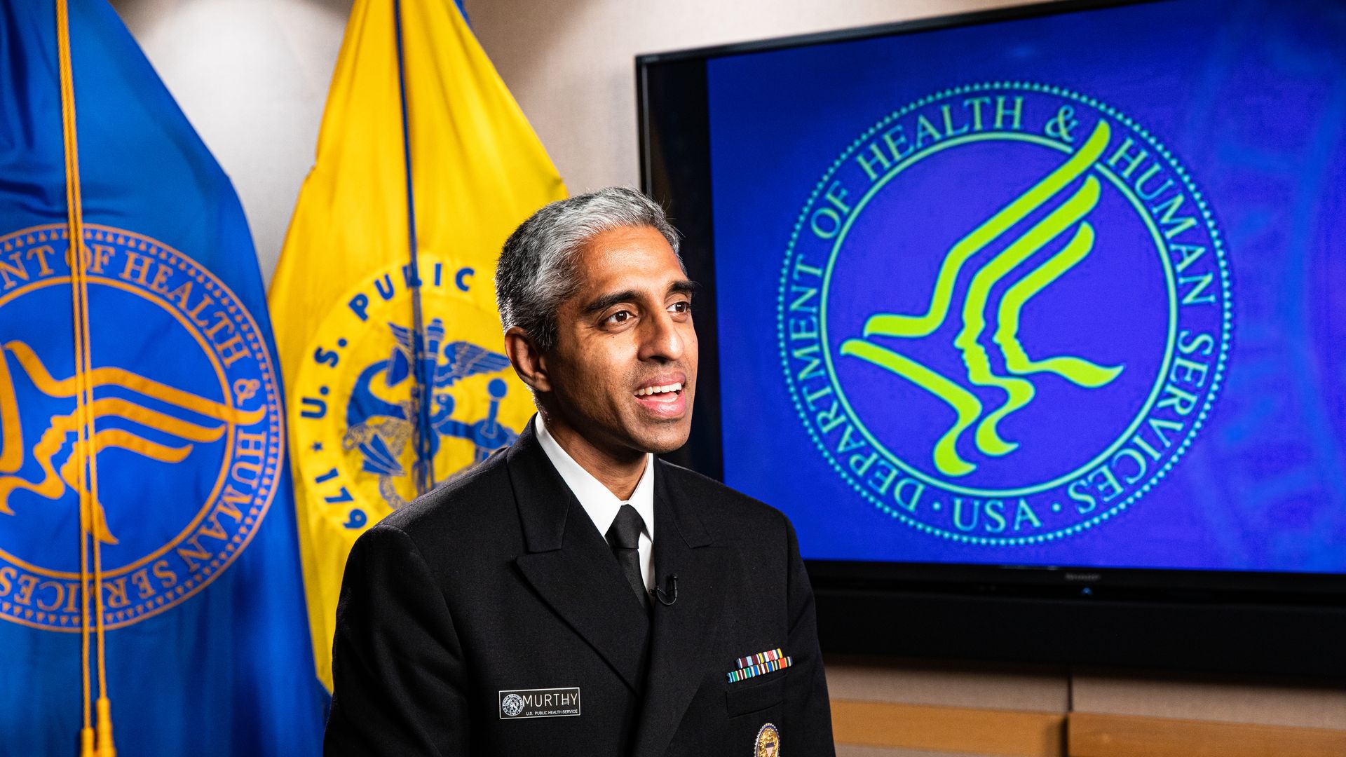 A photo of U.S. Surgeon General Vivek Murthy in front of the HHS logo.