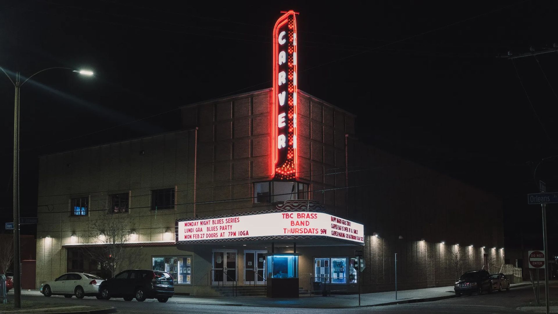 A photo of the Carver Theatre, taken at night, with a marquee lit up with upcoming performances.