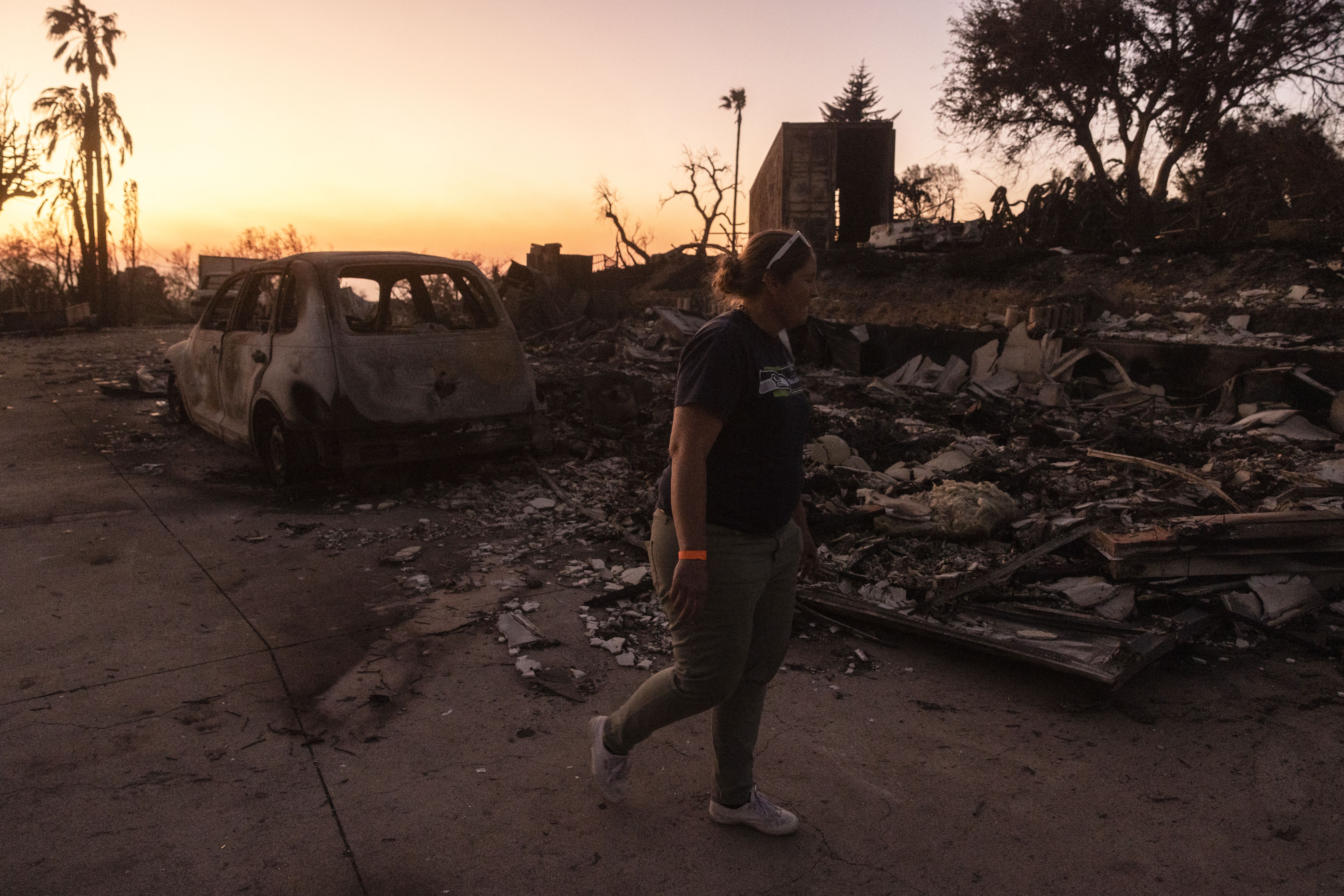A resident walks among the remains of her home destroyed by the Mountain Fire, fueled by strong Santa Ana winds, in Camarillo, California, on November 7, 2024.