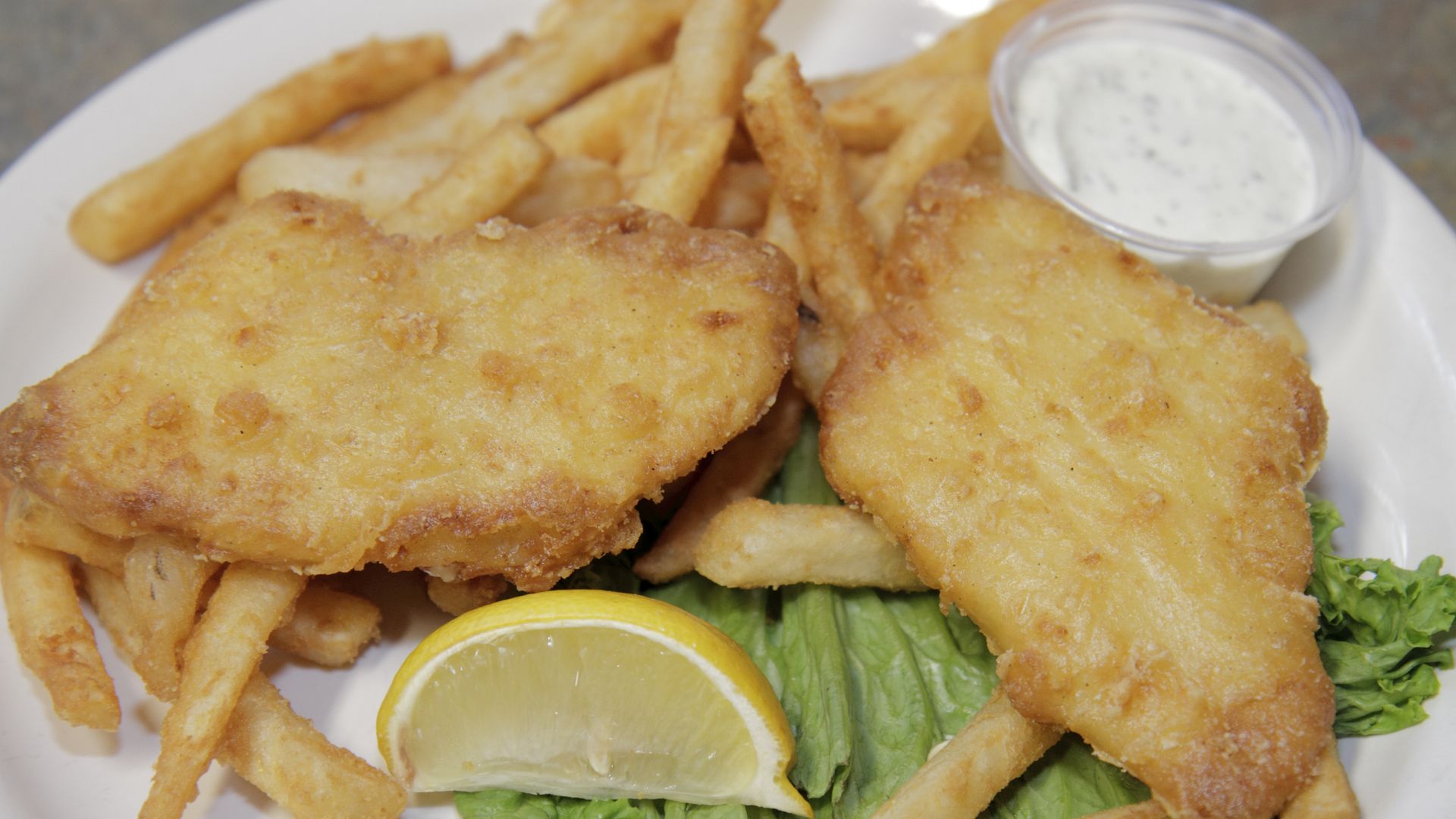 Fried fish with fries, a lemon wedge and tartar sauce