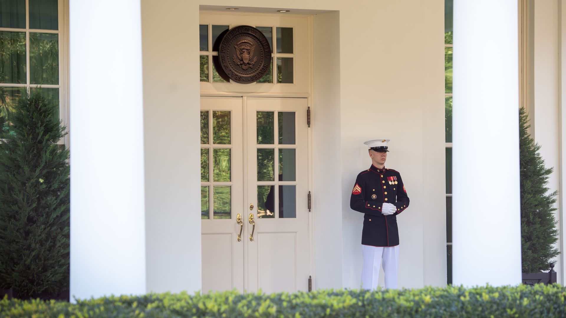 A maskless Marine stands outside a door to the White House