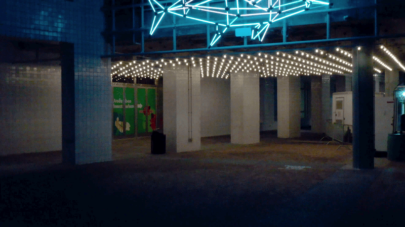 Video pans past a blue lighted sculpture in the shape of a fish.