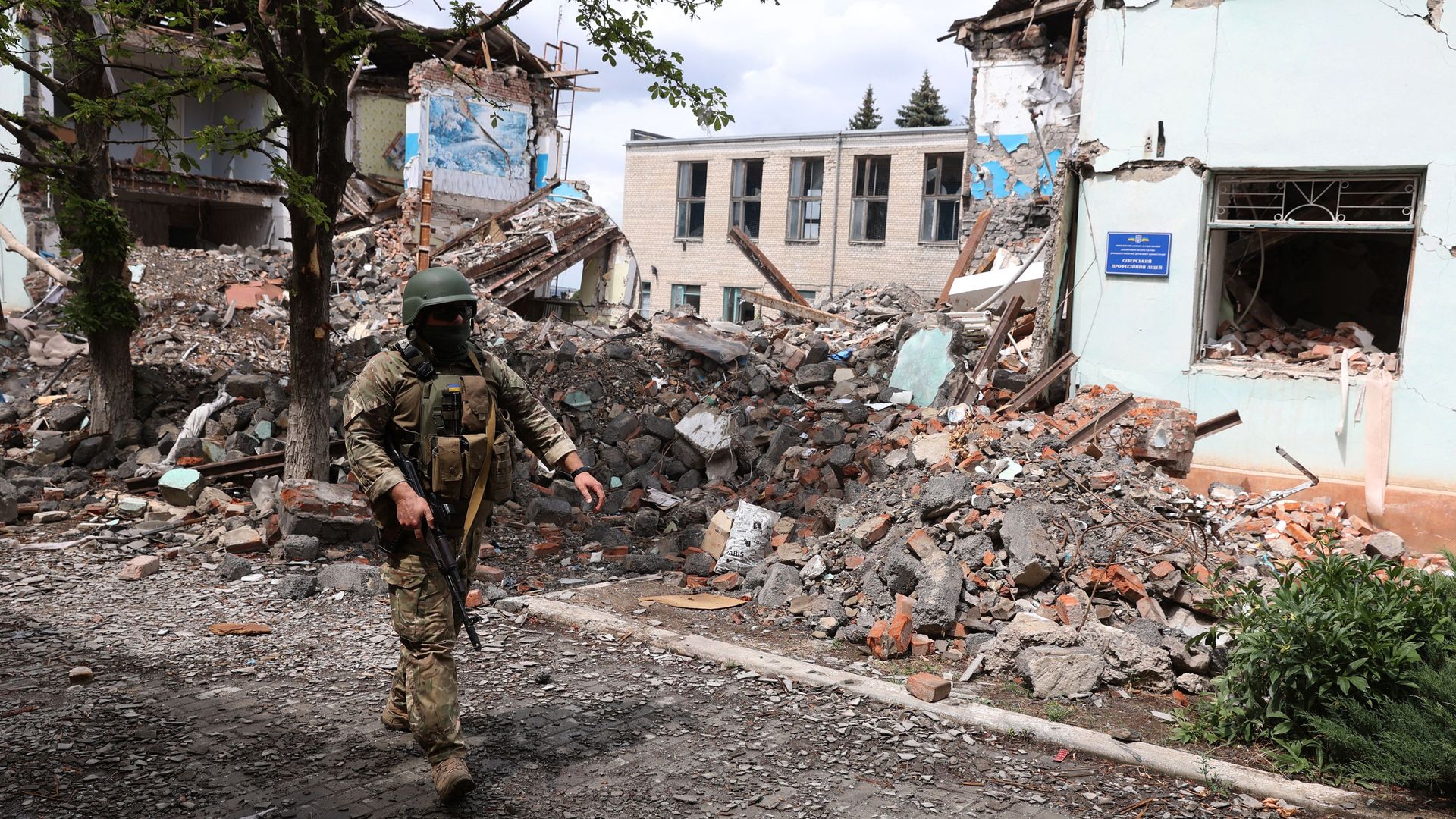 A Ukrainian serviceman passes by destroyed buildings