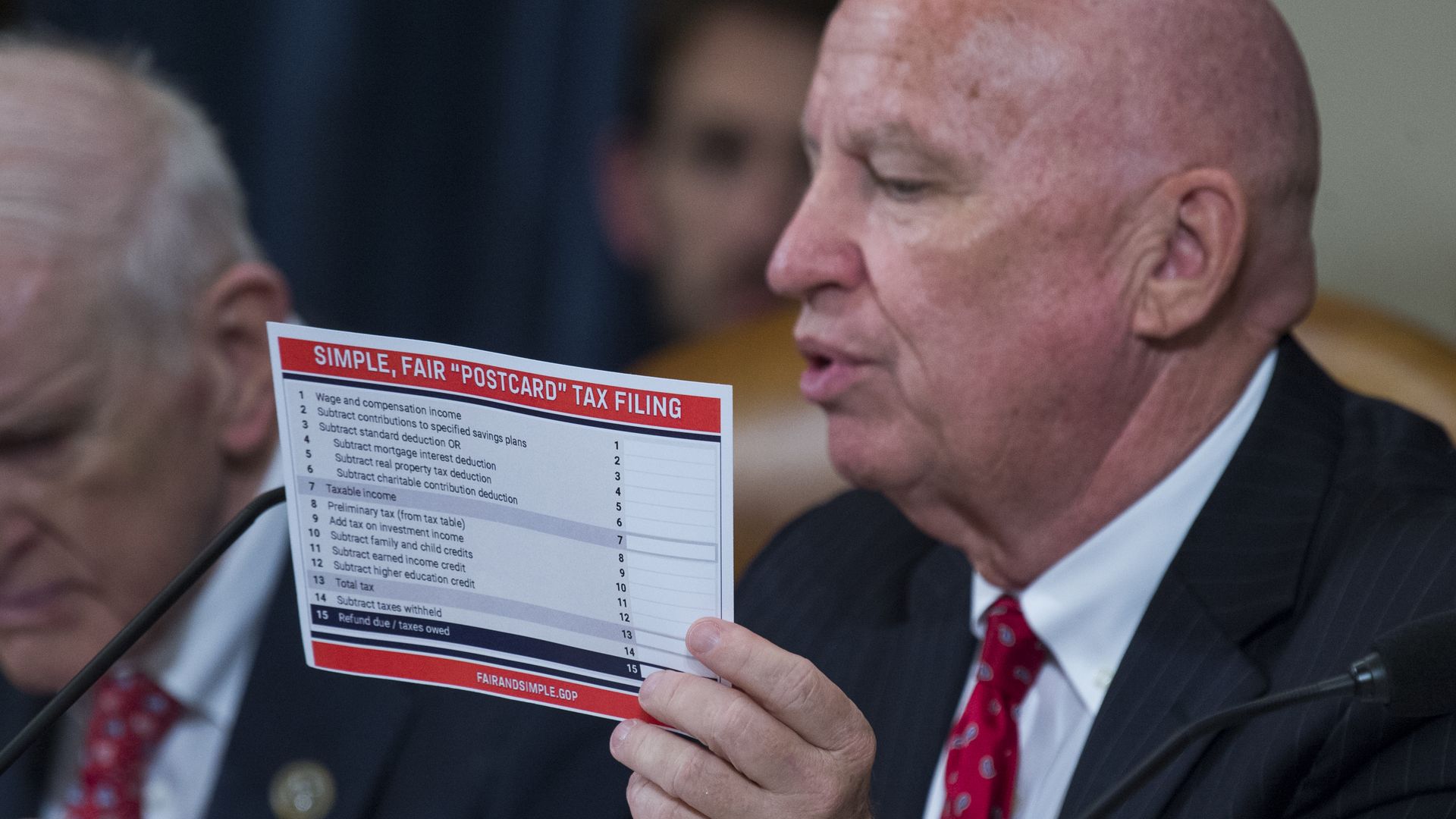 Man holding up postcard size paper.