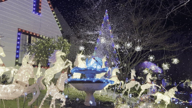 Animated gif shows a front yard decorated for Christmas with numerous illuminated unicorns and fake snow falling from the sky.