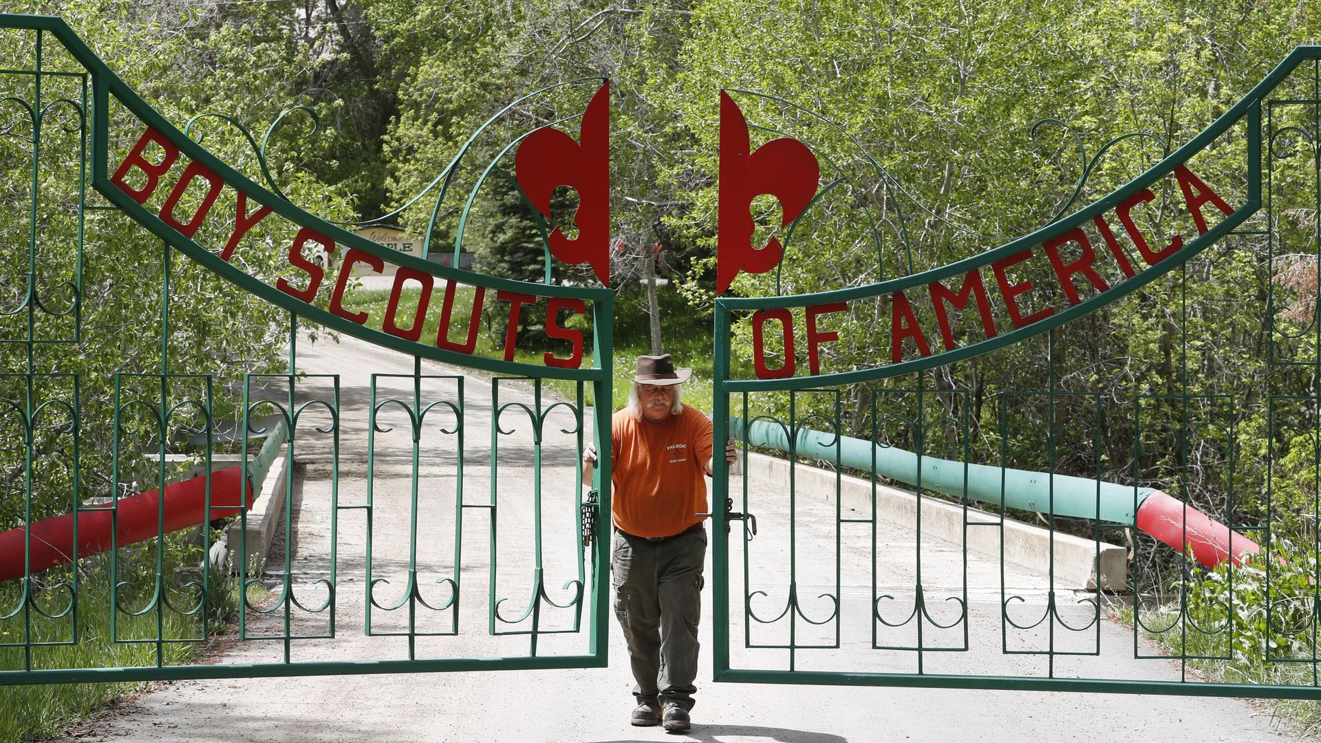 Photo of a camp ranger opening up a gate that has the words "Boy Scouts of America"