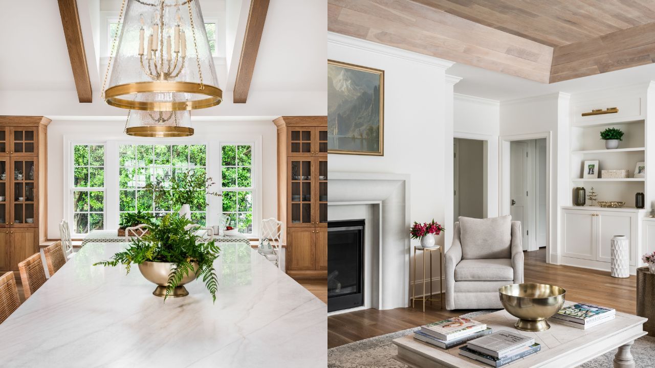 Bright dining room with large white marble table, wooden chairs, green plants centerpiece, wood-beamed ceiling, and large windows. Adjacent cozy living room with gray chair, fireplace, and brass decor.