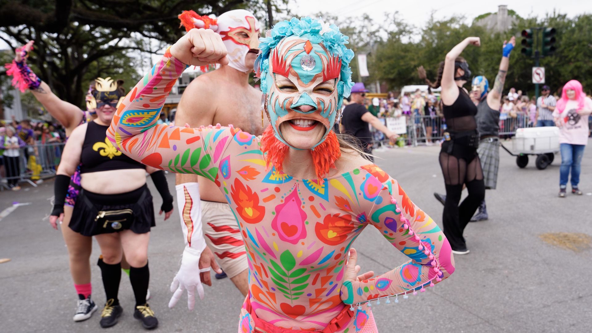 Image shows a woman in a multi-colored lucha costume with a face covering.