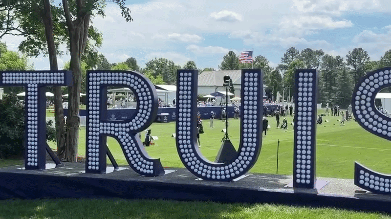 GIF of a sign made out of golf balls reading "Truist" in front of a driving range. 