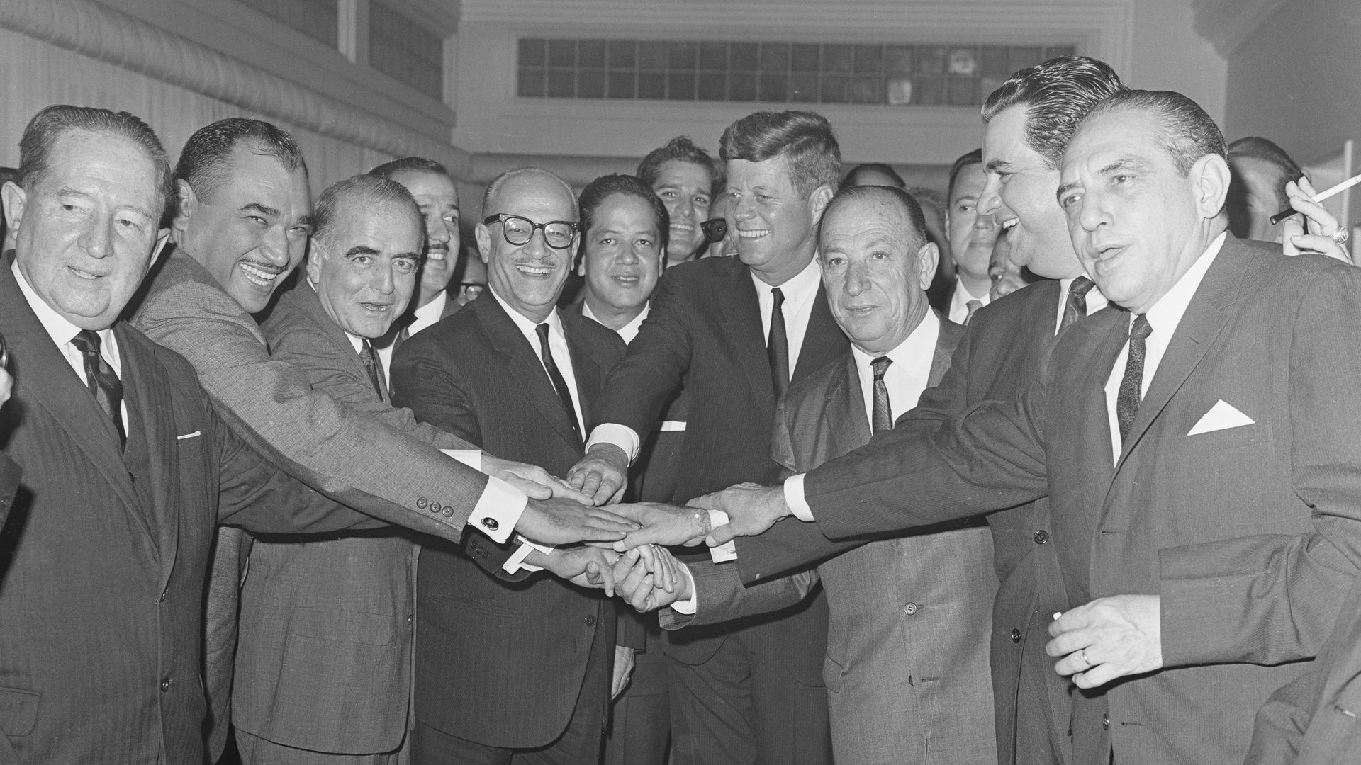President Kennedy joins in an eight-way handshake with presidents from Central American nations.