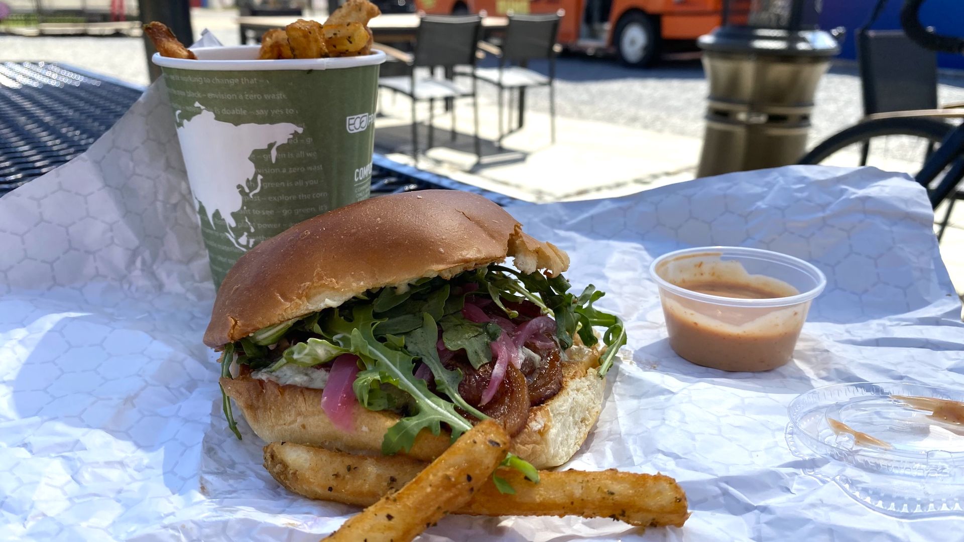 A burger and fries on an outdoor table.