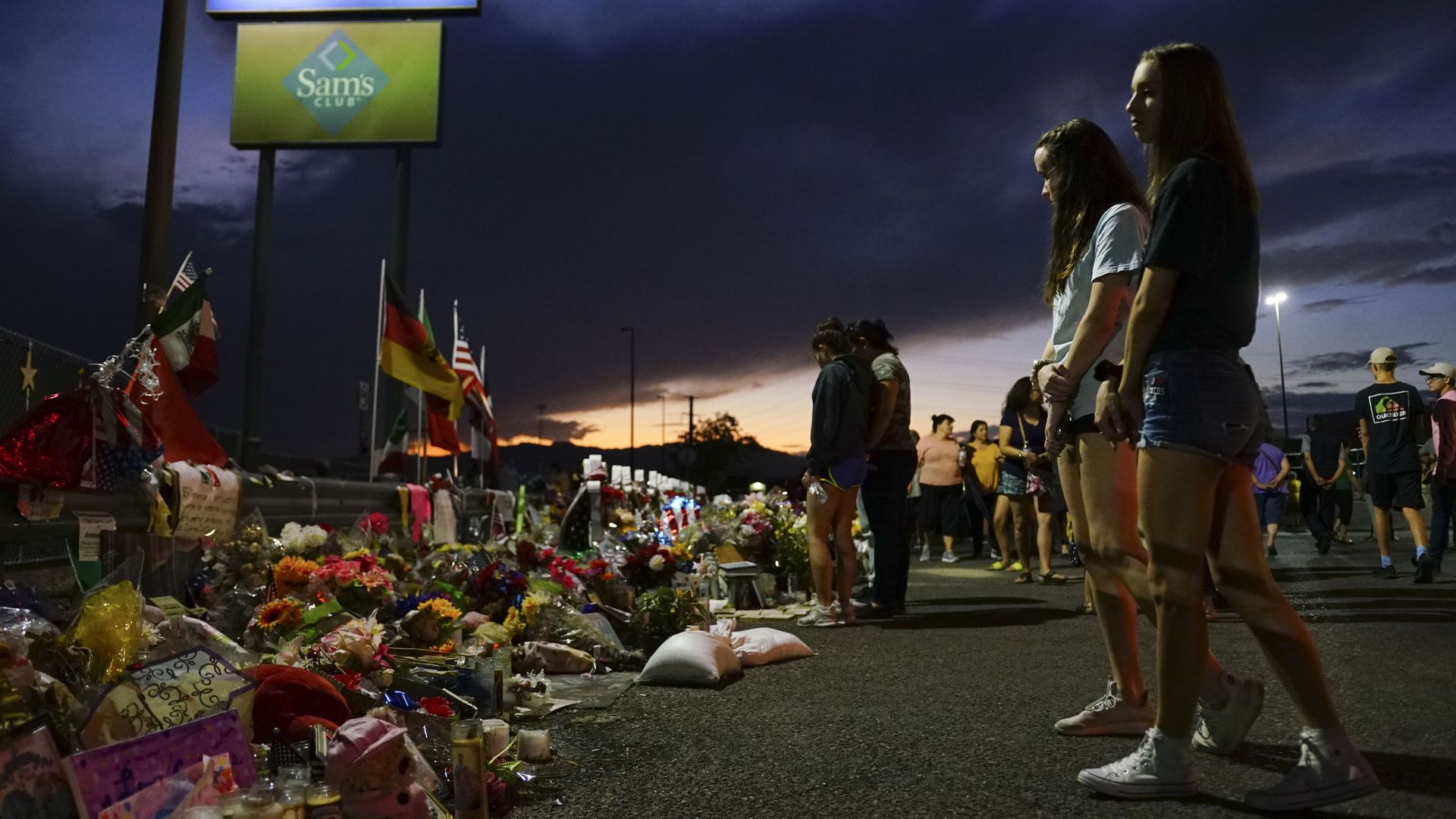 People look at flowers laid out to honor the victims of the El Paso shooting. 