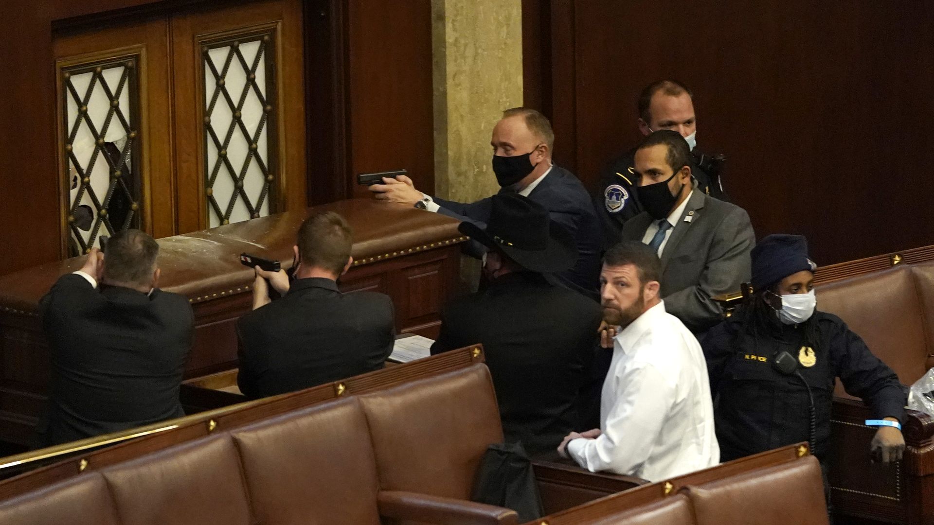 People point guns outside a room.