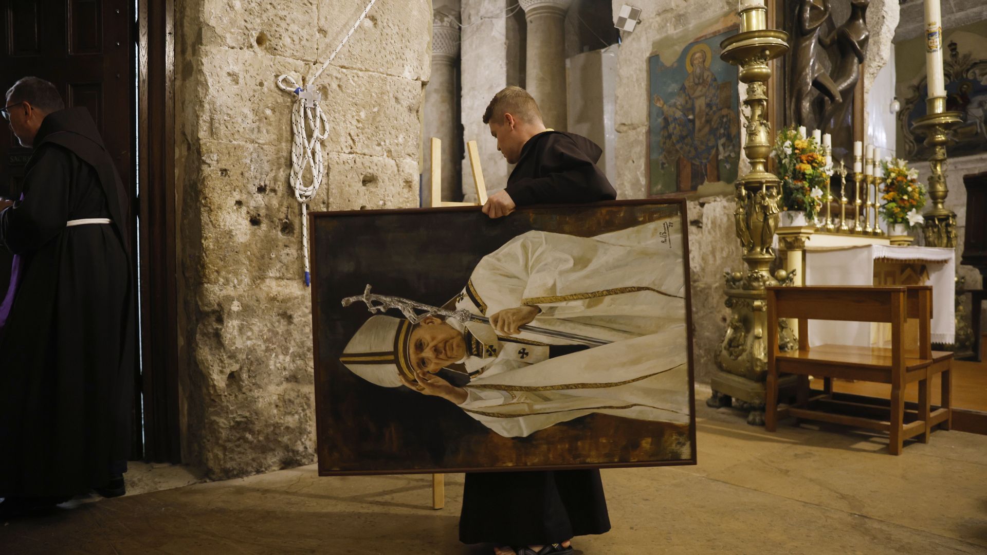 A priest holds a portrait of Pope Francis 