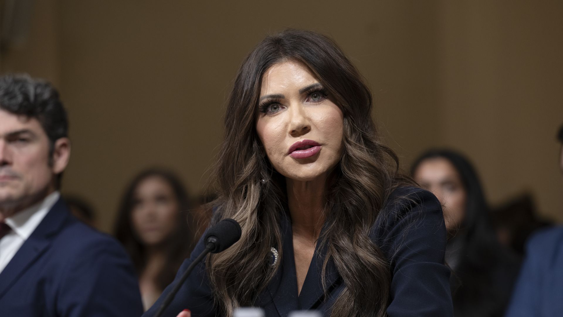 Kristi Noem, secretary of the Department of Homeland Security, seated at a witness table answering questions at a House Committee on Homeland Security hearing on worldwide threats in Washington, D.C., with microphones and committee members visible.