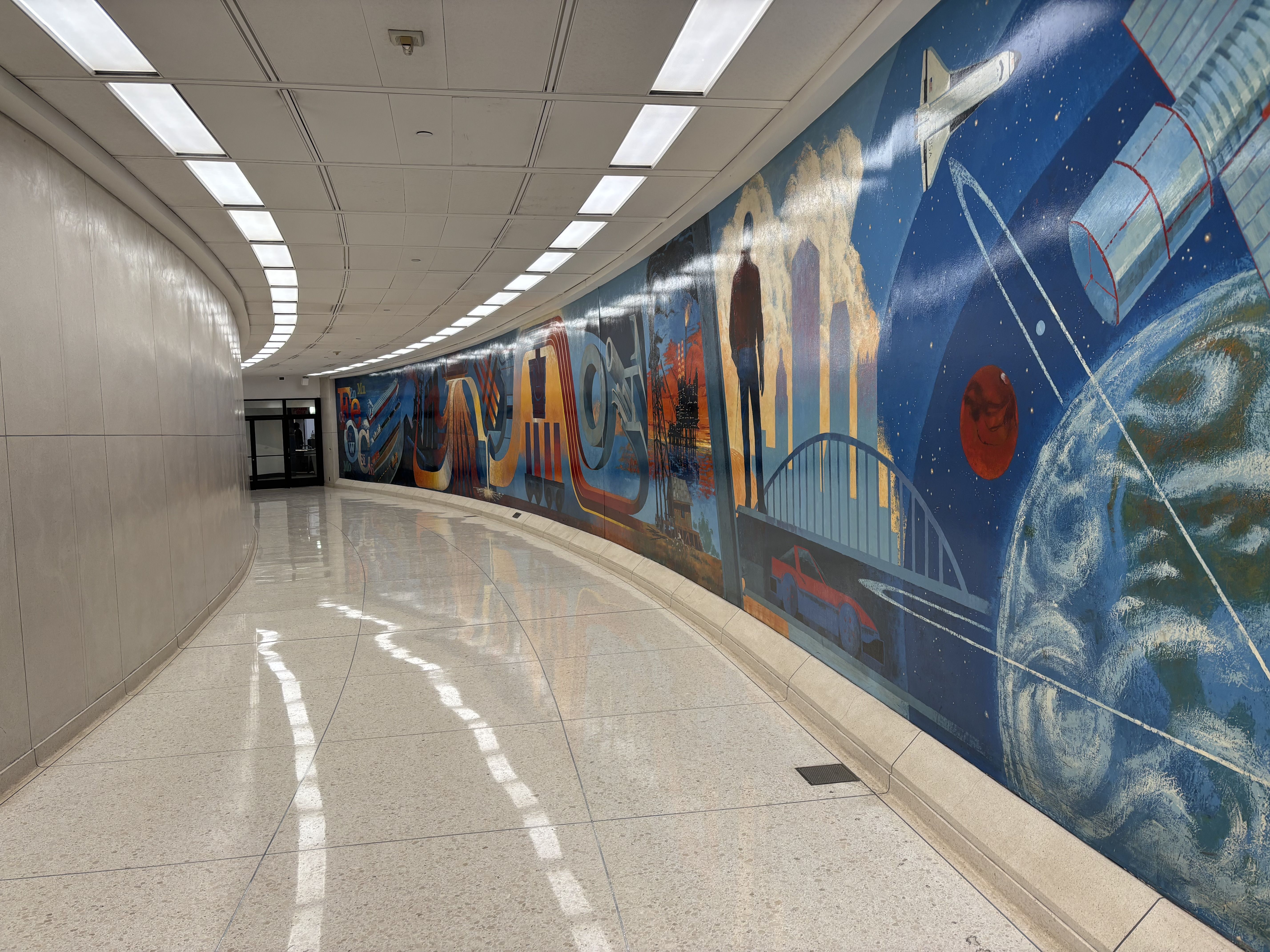 A hallway with a large mural that connects the U.S. Steel tower to the Steel Plaza subway station