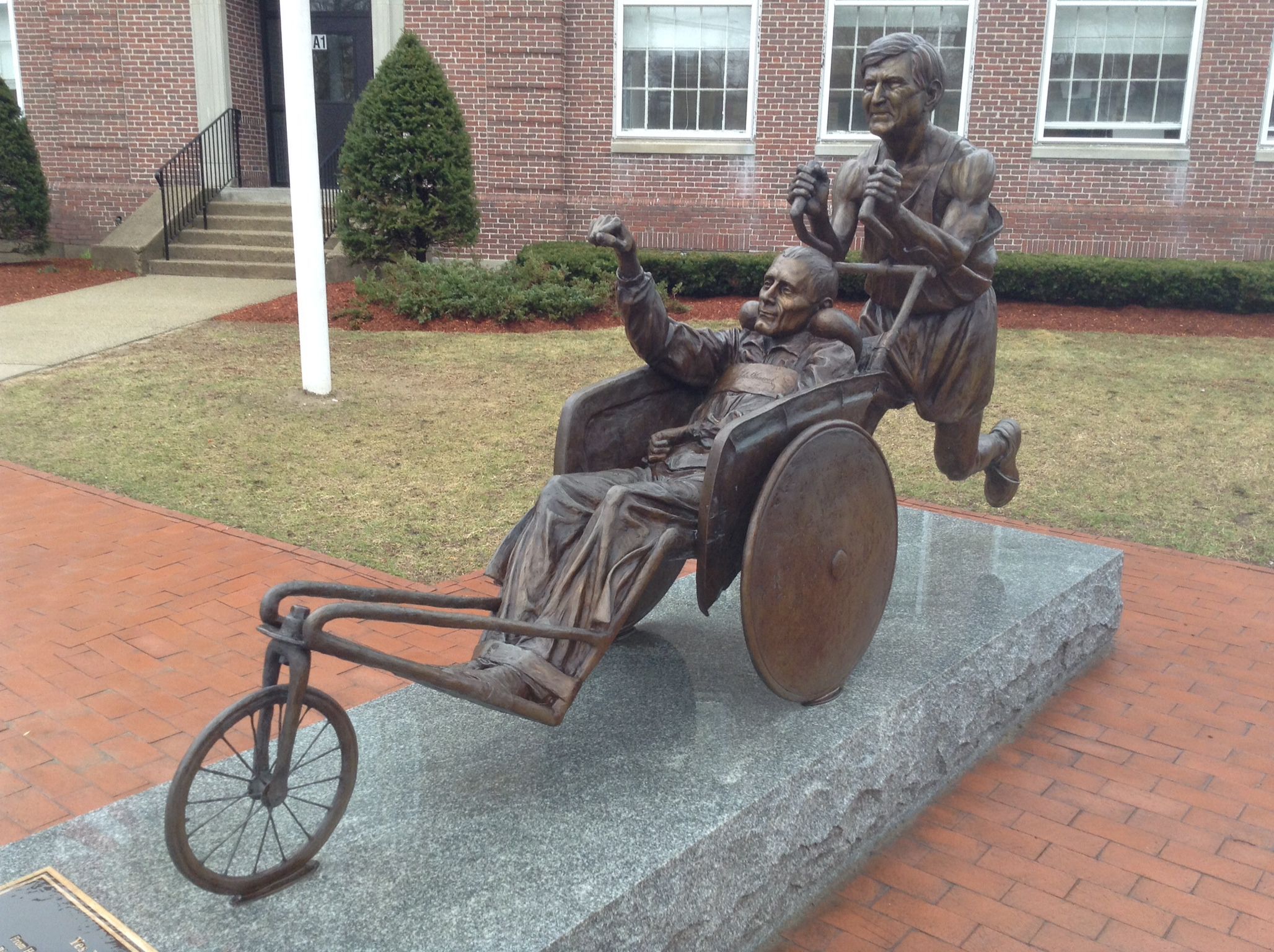 A statue of a man pushing a boy in a wheelchair.