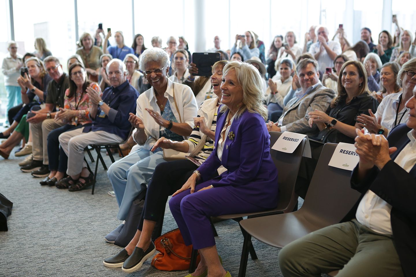 Jill Biden sits in the front row of a New Orleans Book Festival crowd as everyone around her turns and applauds.